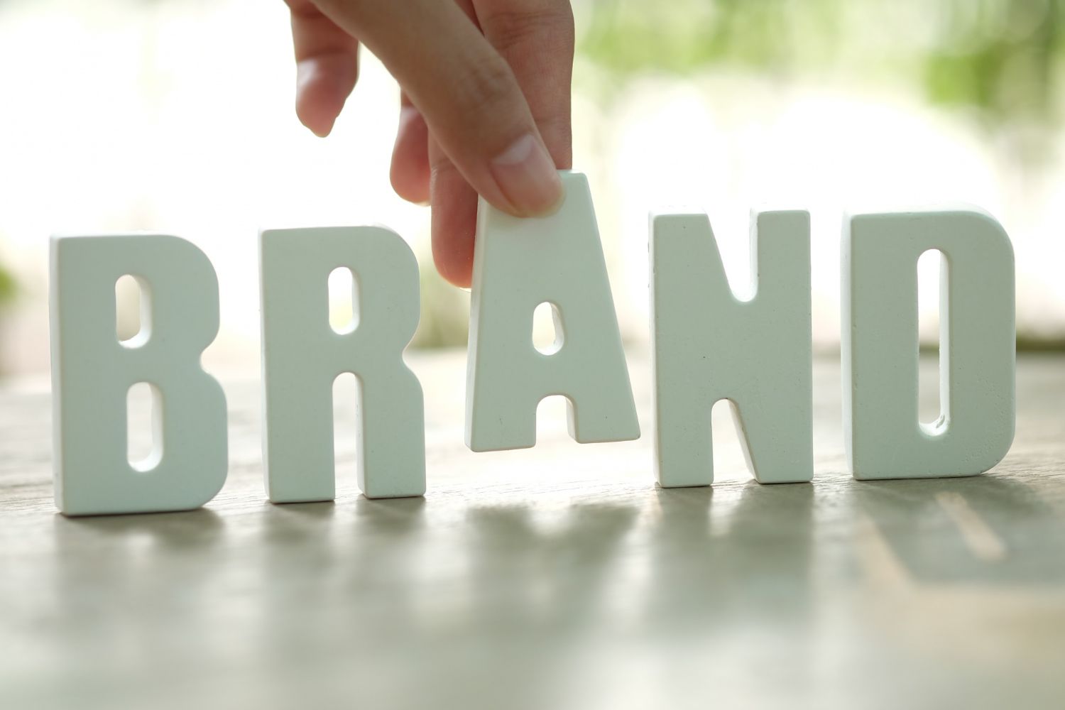A person is putting a piece of paper in the word brand.