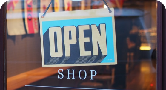 An open shop sign hangs in a store window