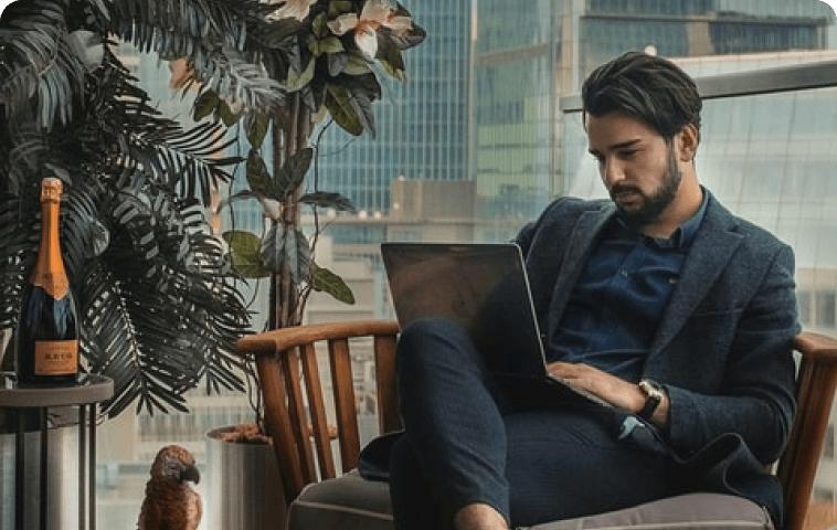A man in a suit is sitting in a chair using a laptop computer.