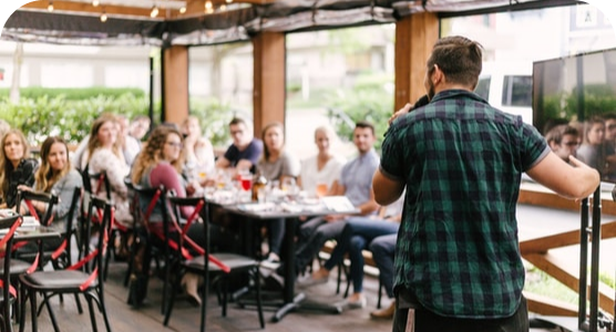 A man is giving a presentation to a group of people in a restaurant.