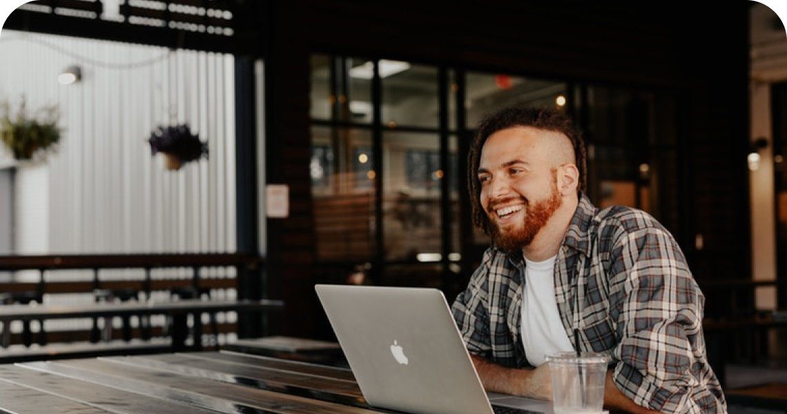 A man is sitting at a table using a laptop computer.