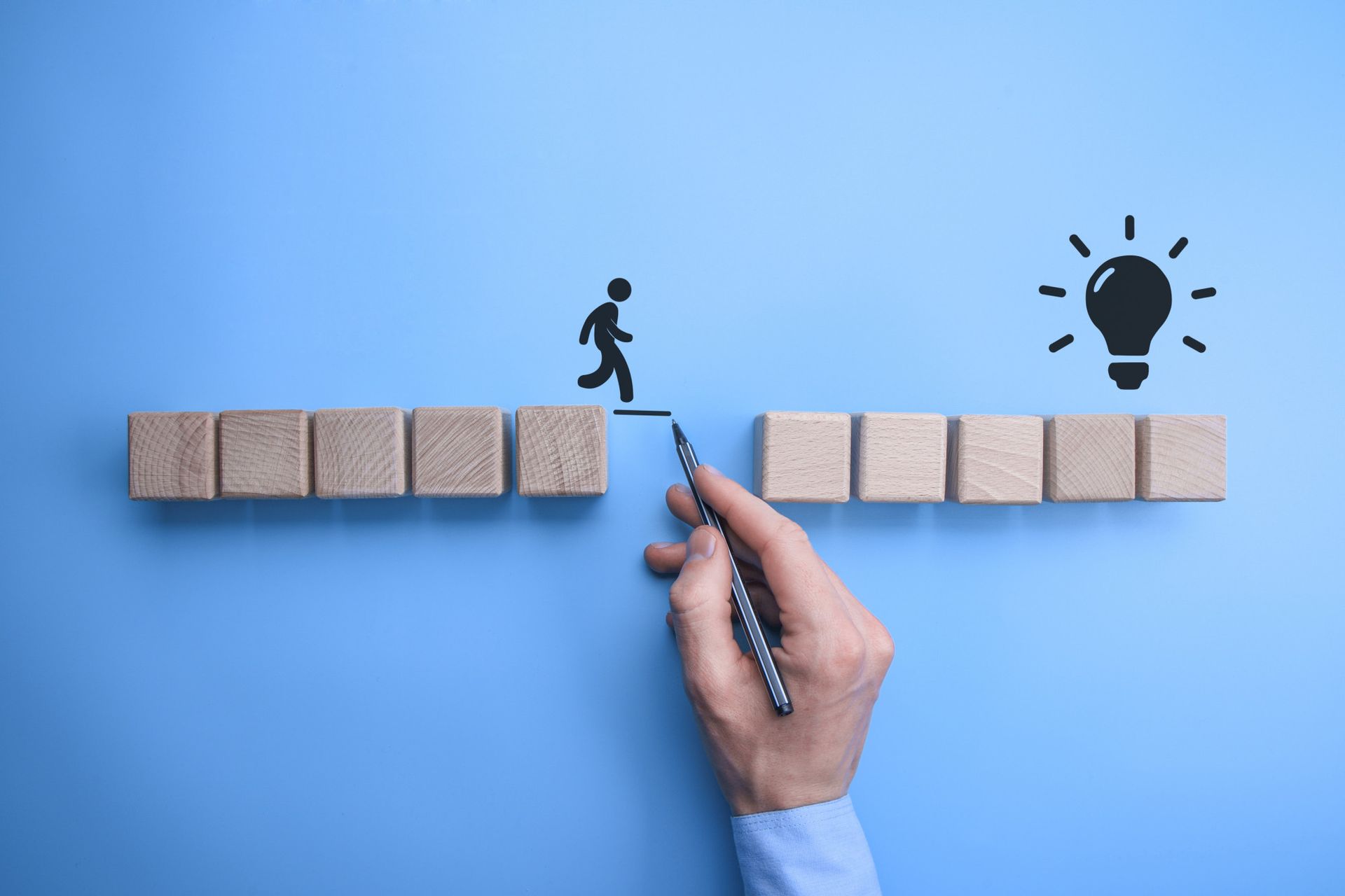 A person is drawing a man walking up a staircase made of wooden blocks.