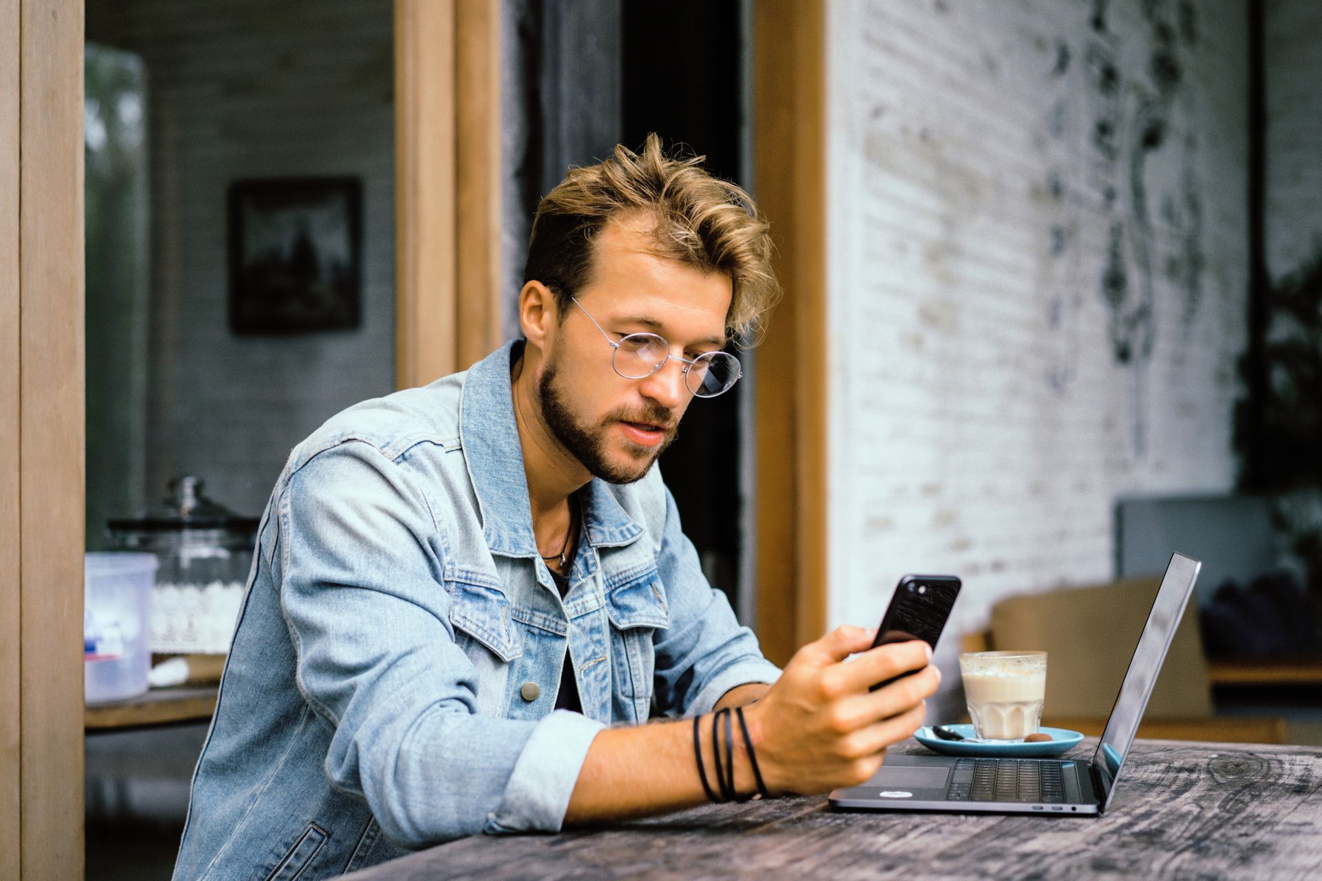 A man is sitting at a table looking at his cell phone.
