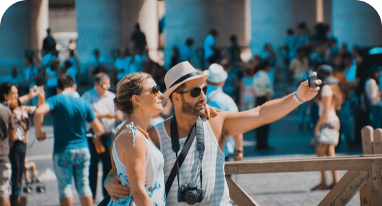 A man and a woman are taking a selfie in front of a crowd of people.