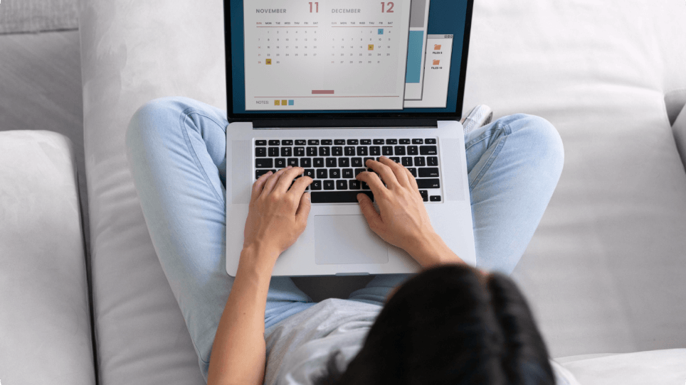 A woman is sitting on a couch using a laptop computer.