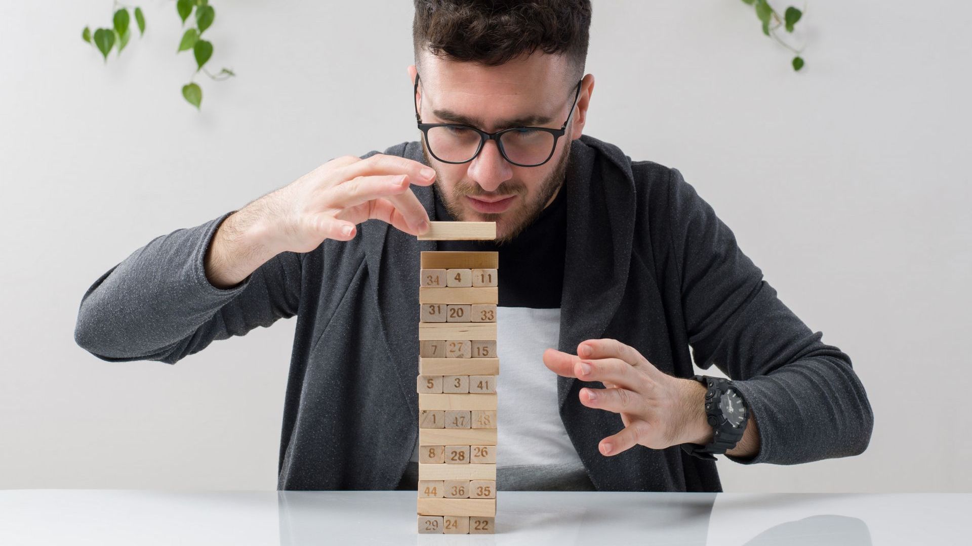 A man is sitting at a table playing a game of jenga.