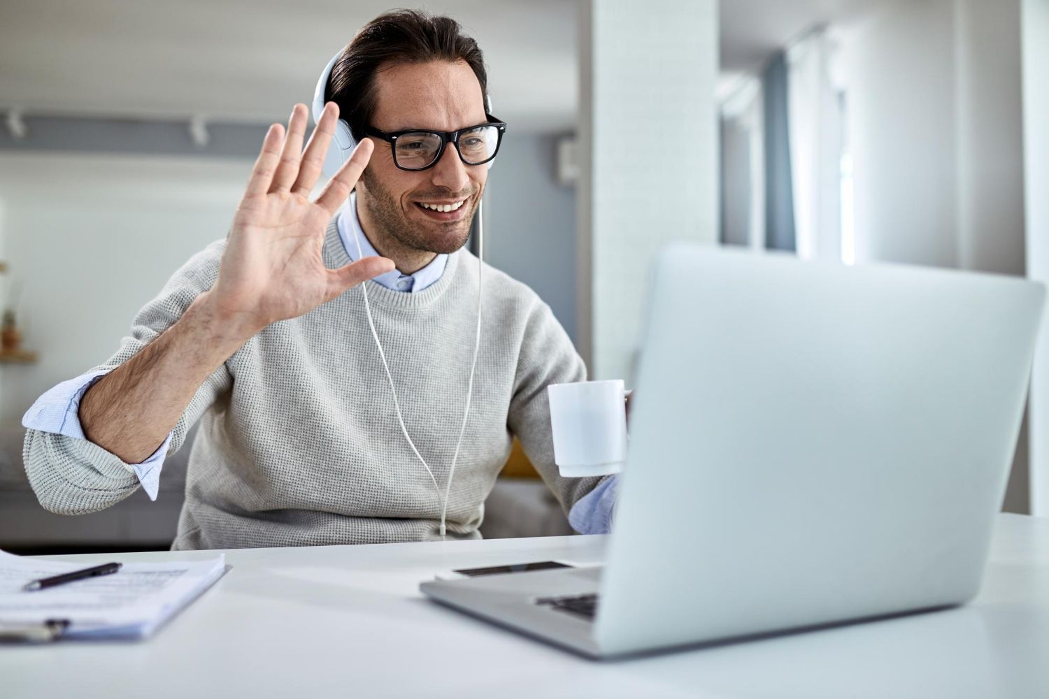 A man is sitting at a desk using a laptop computer while wearing headphones.