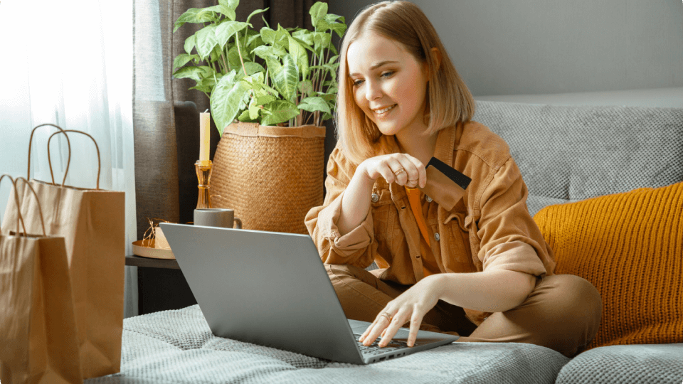 A woman is sitting on a couch using a laptop computer.