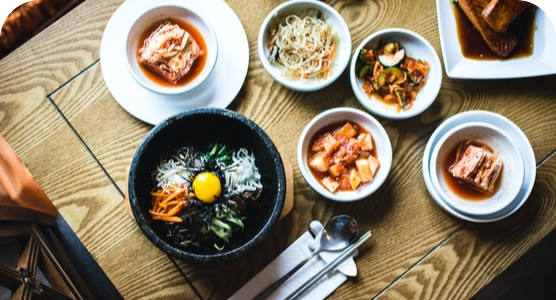 A wooden table topped with bowls of food and chopsticks.