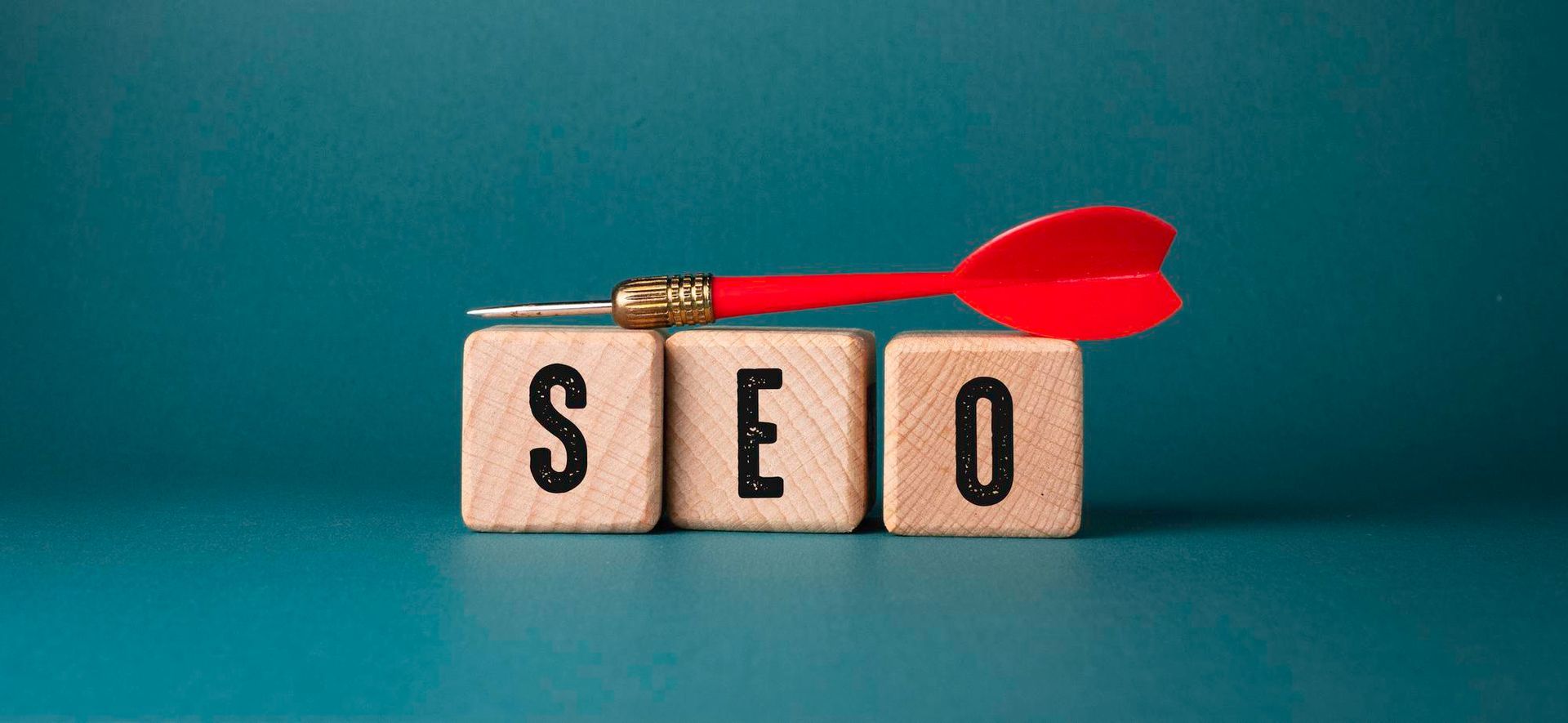 The word seo is written on wooden blocks next to a dart.