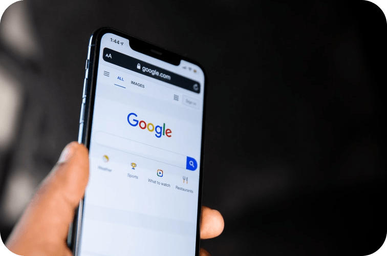A person is holding a cell phone with google on the screen.