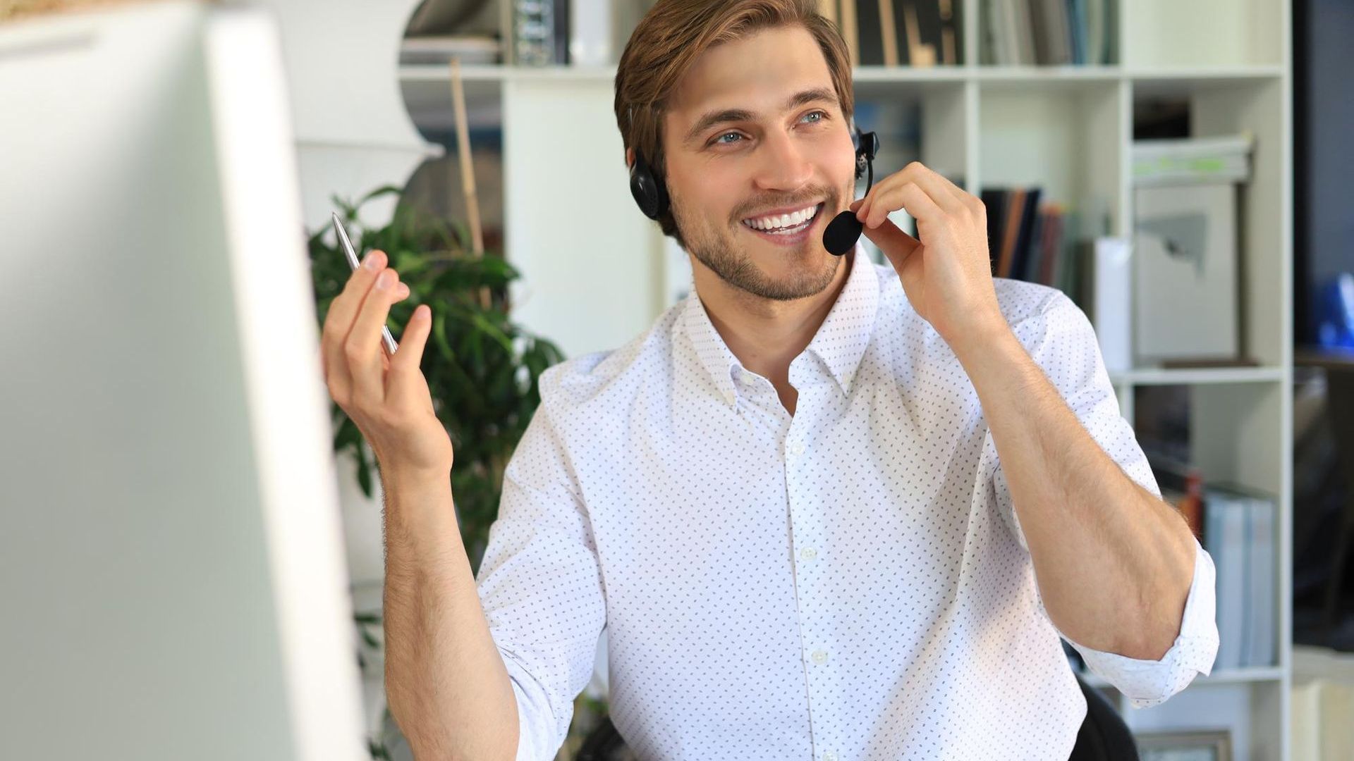 A man wearing a headset is sitting in front of a computer.