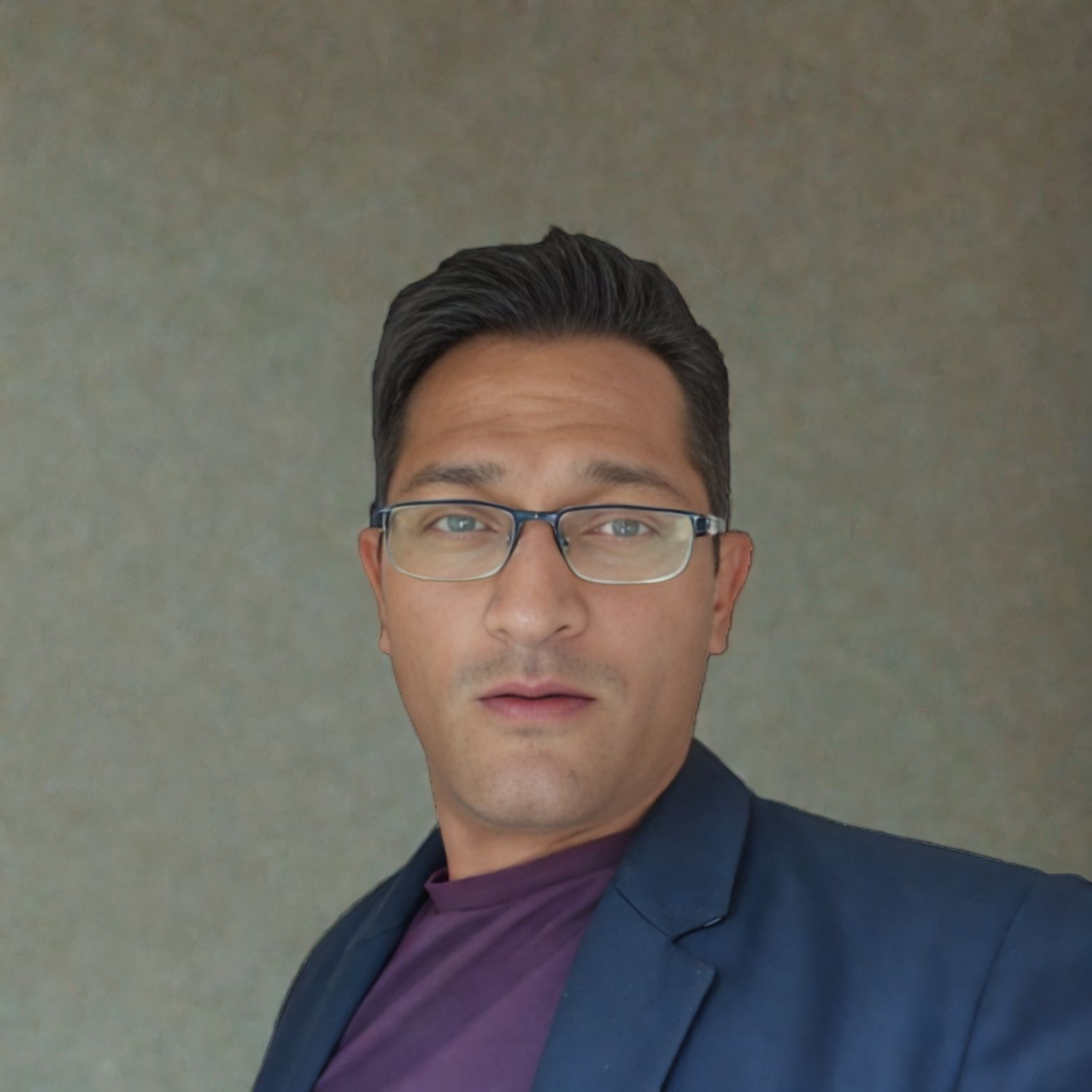 A man wearing glasses and a suit looks at the camera