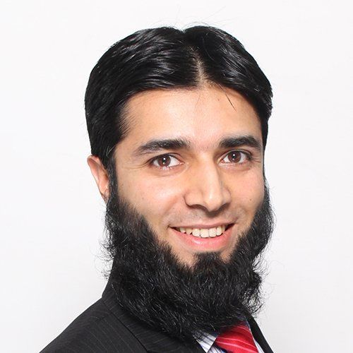 A man with a beard is wearing a suit and tie and smiling.