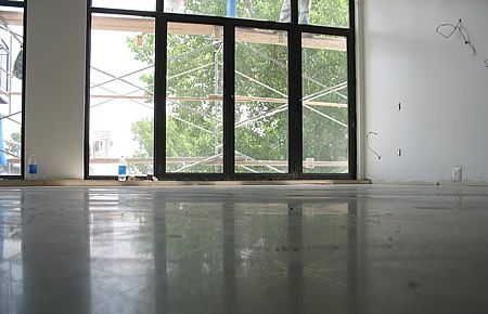 An empty room with a lot of windows and a concrete floor.