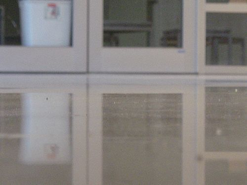 A white cabinet with glass doors and a white bucket in it.