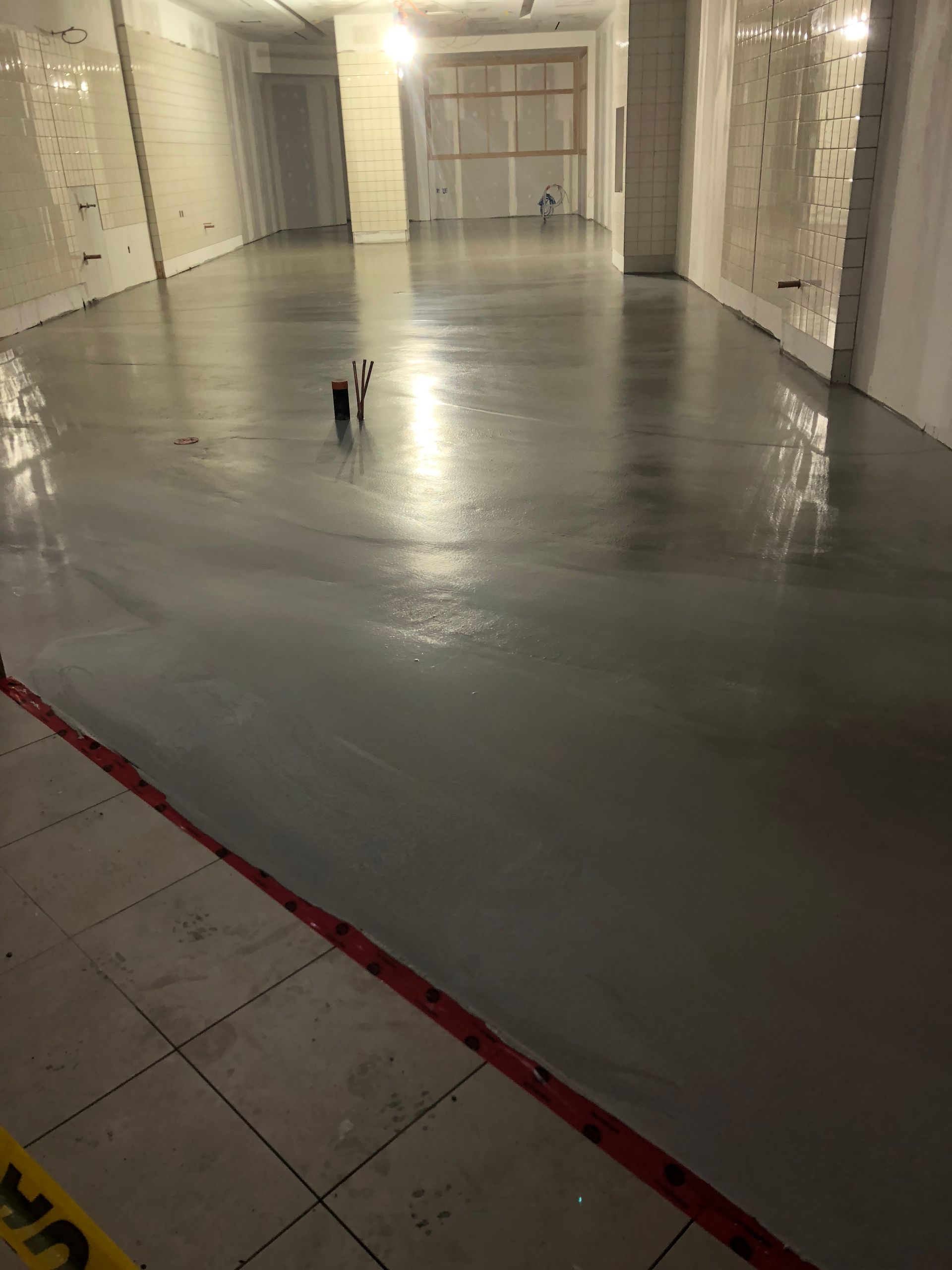 A large empty room with a concrete floor and a yellow caution tape.