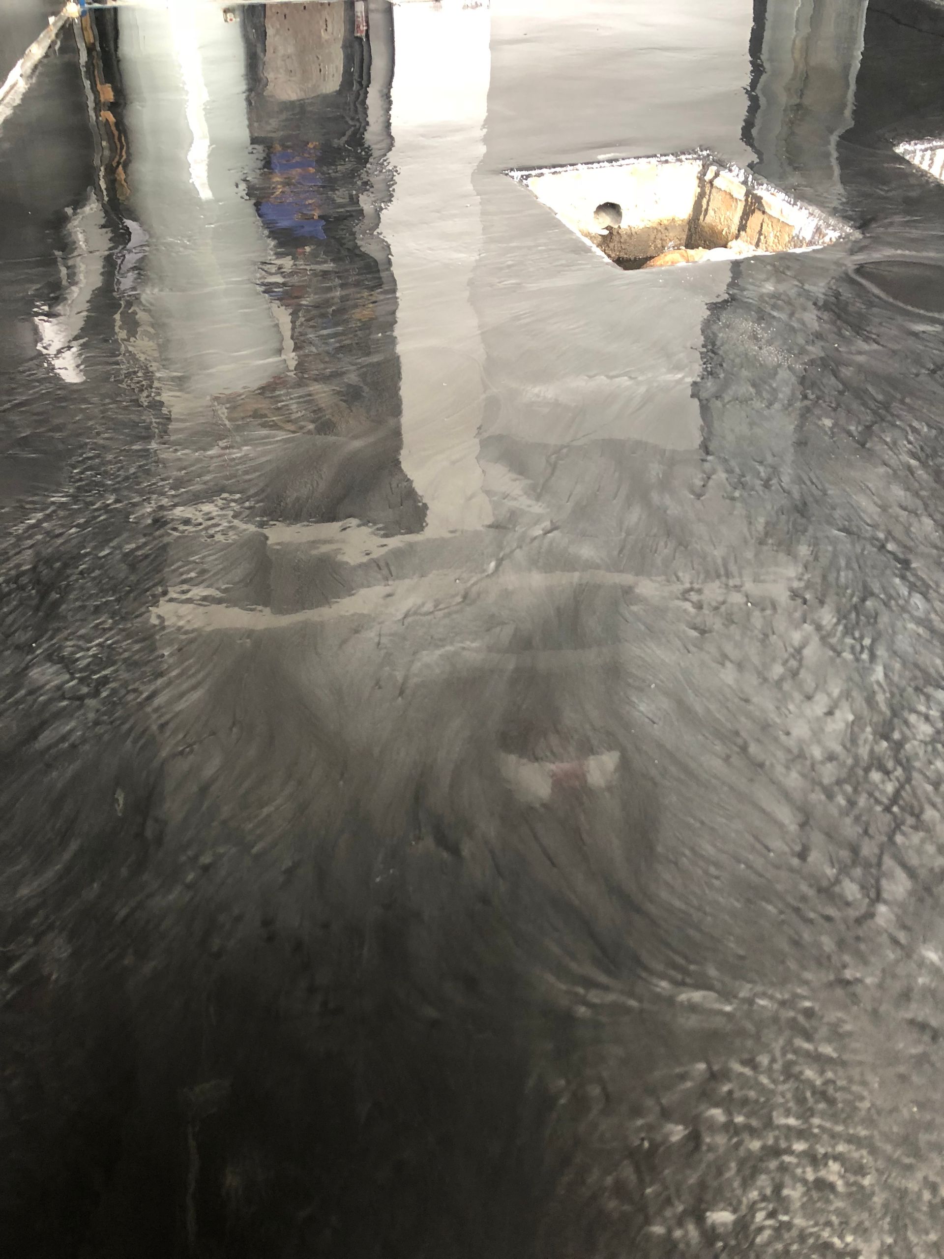 A reflection of a building in a puddle of water on a wet floor.