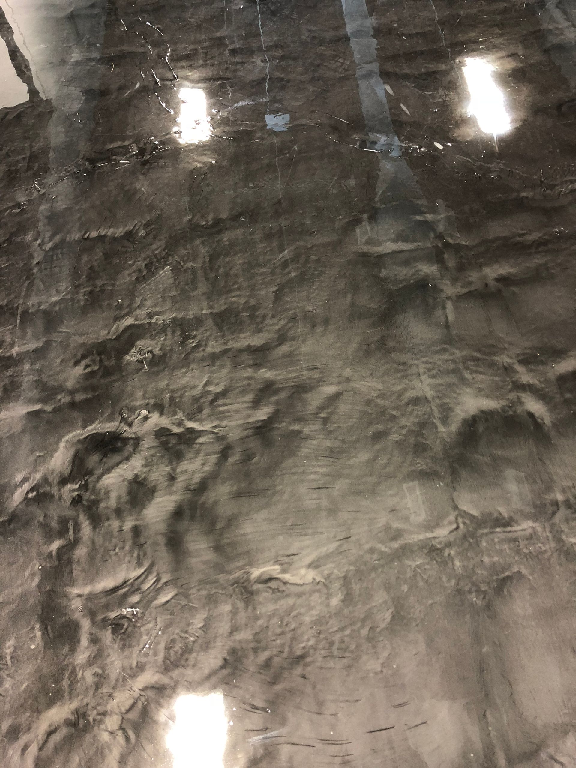 A close up of a shiny metallic floor with lights reflected in it.