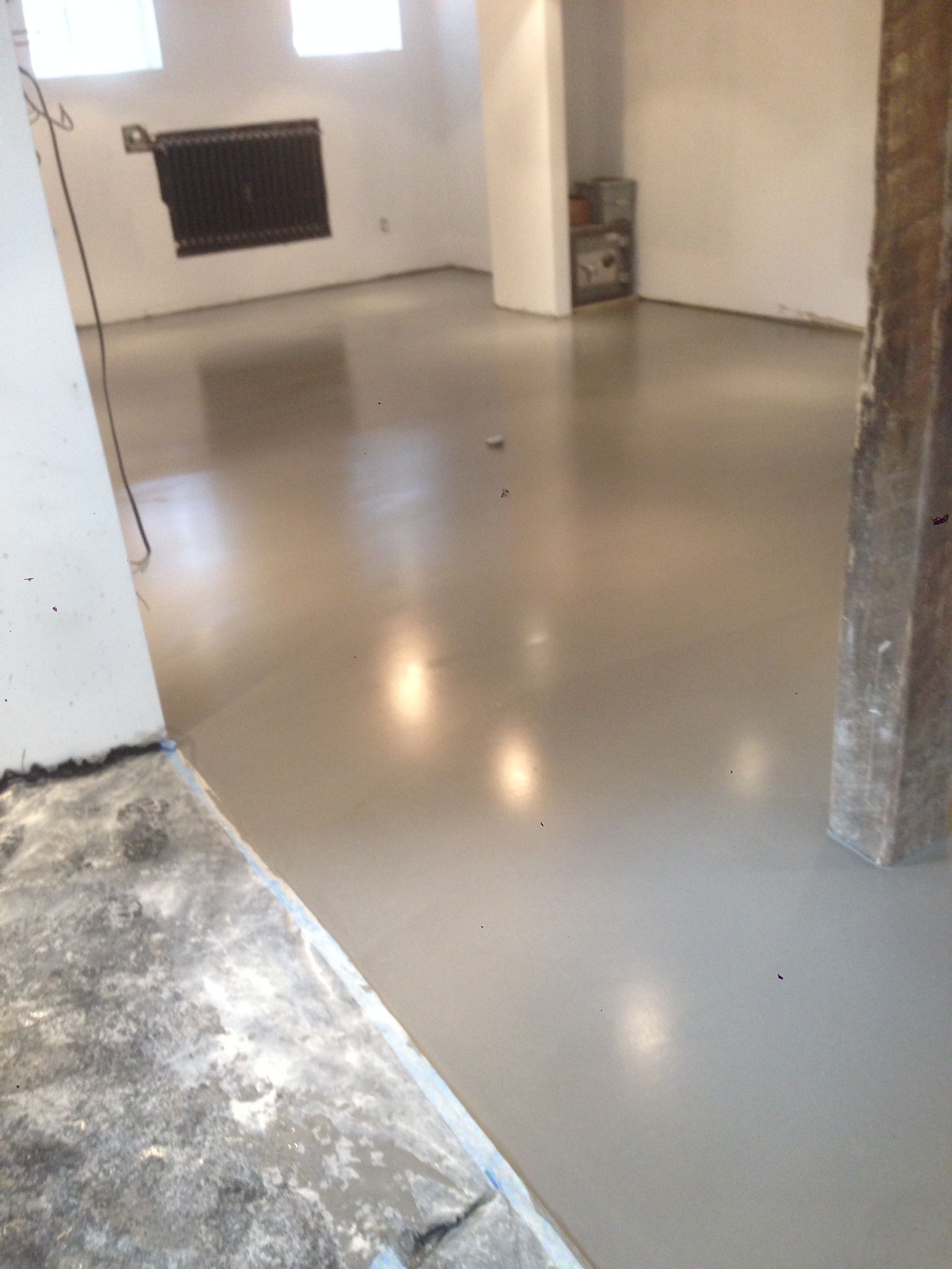 A room with a concrete floor and a pillar in the corner.