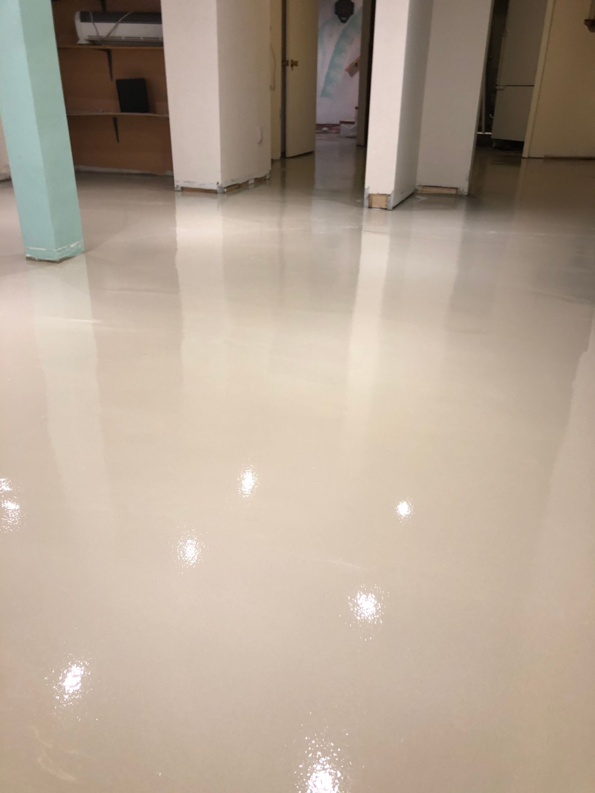 A white floor in a room with a green pillar.