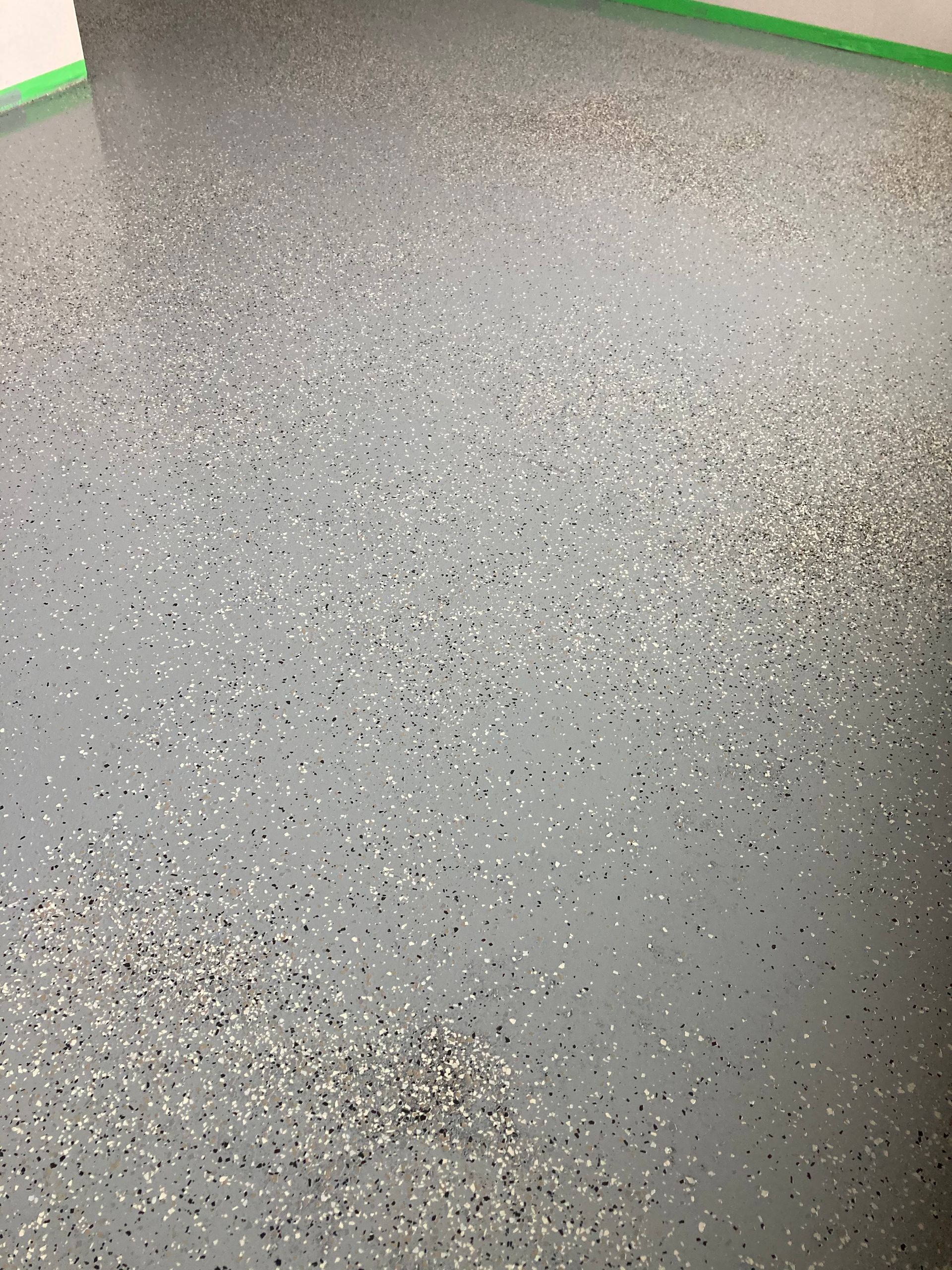 A close up of a gray and white floor with a green border.