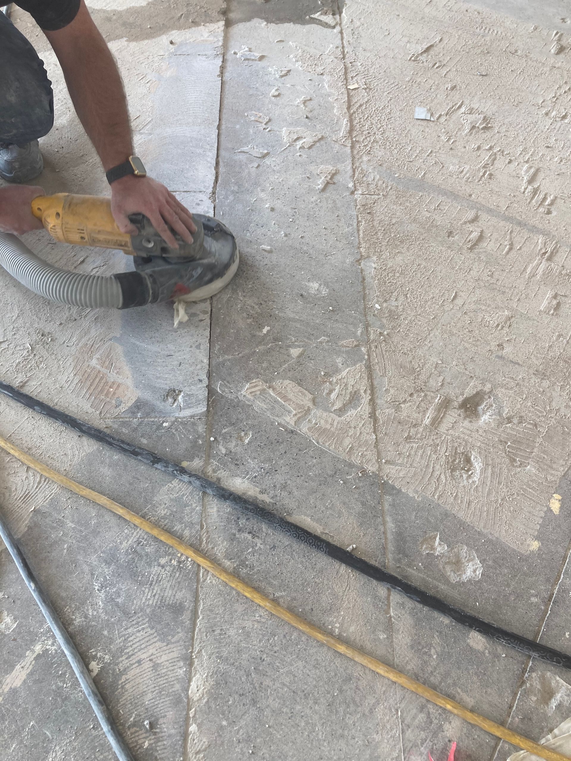 A man is sanding a tile floor with a machine