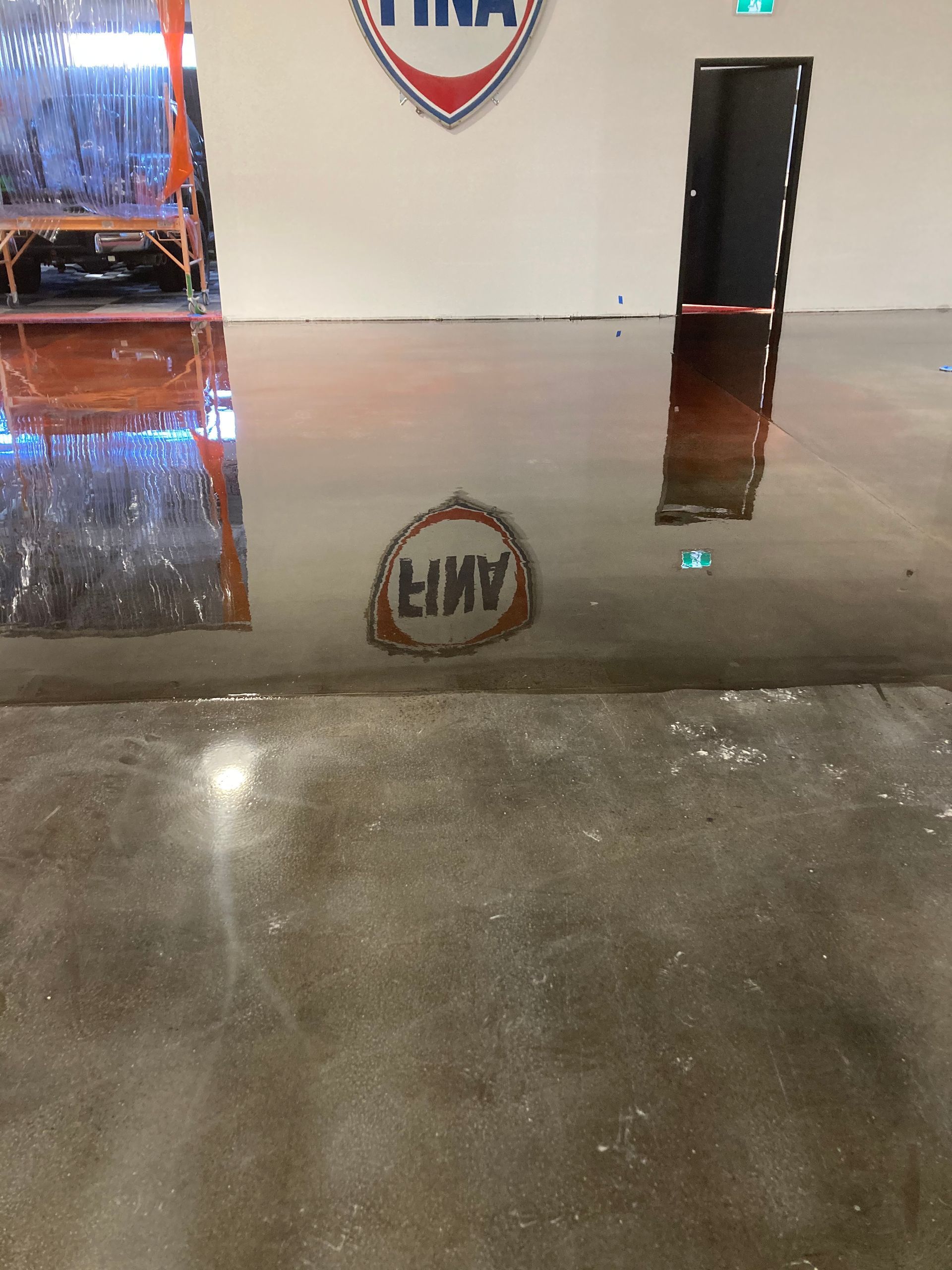 A shiny concrete floor with a reflection of a sign that says amir