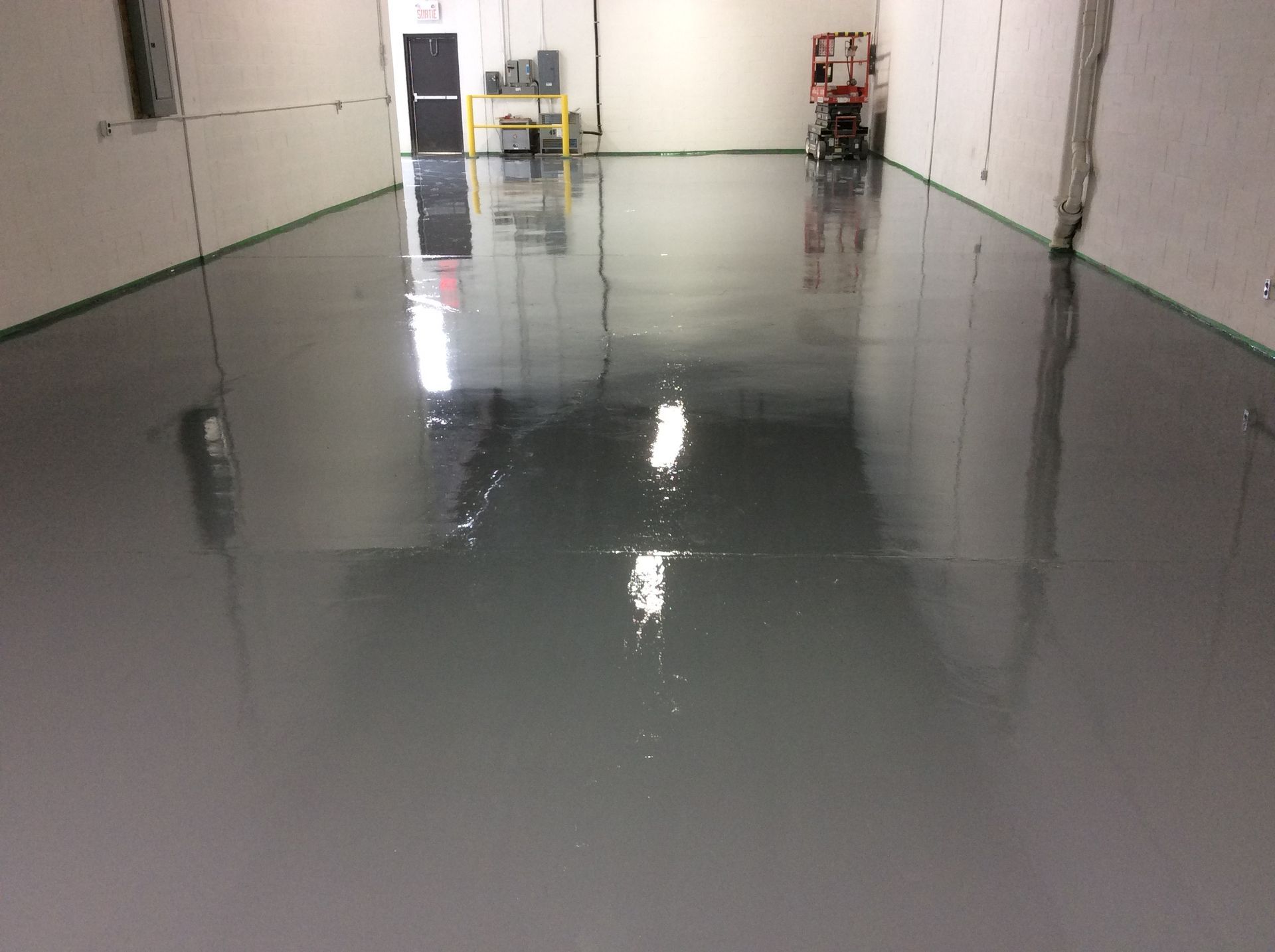A large room with a concrete floor and a reflection of a person in the floor.