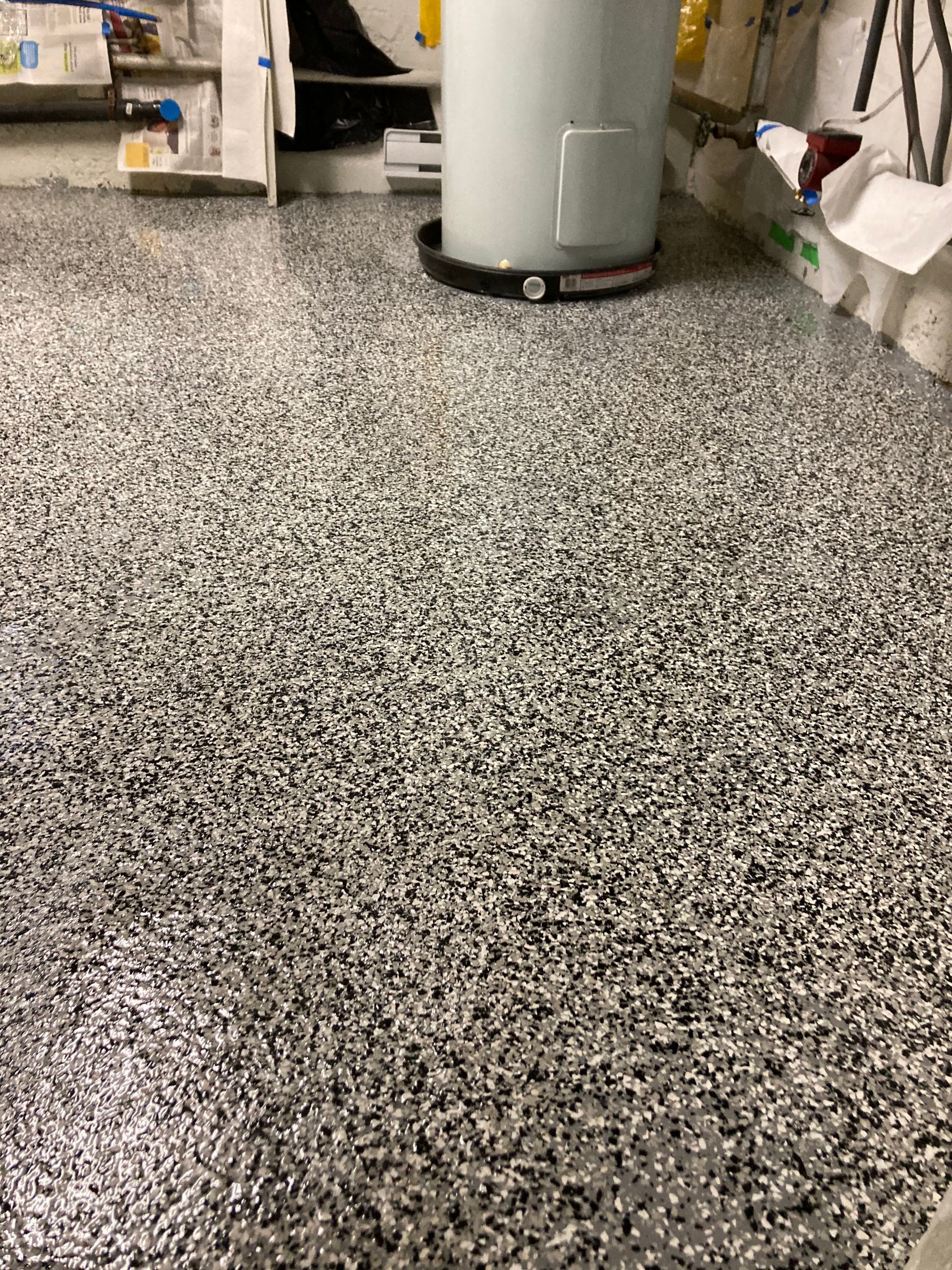 A gray and white floor with a water heater in the background.