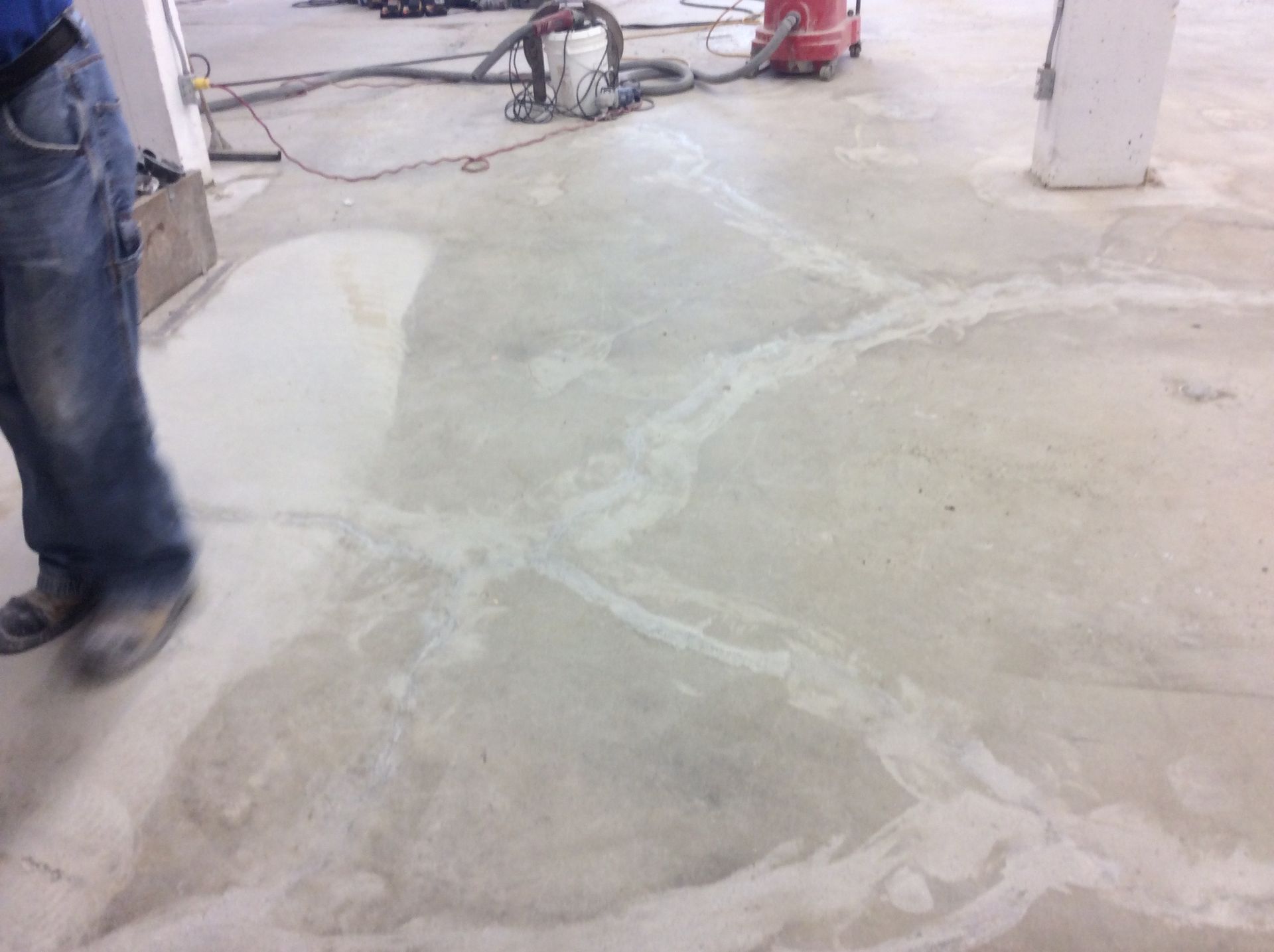 A person is standing on a concrete floor next to a vacuum cleaner.