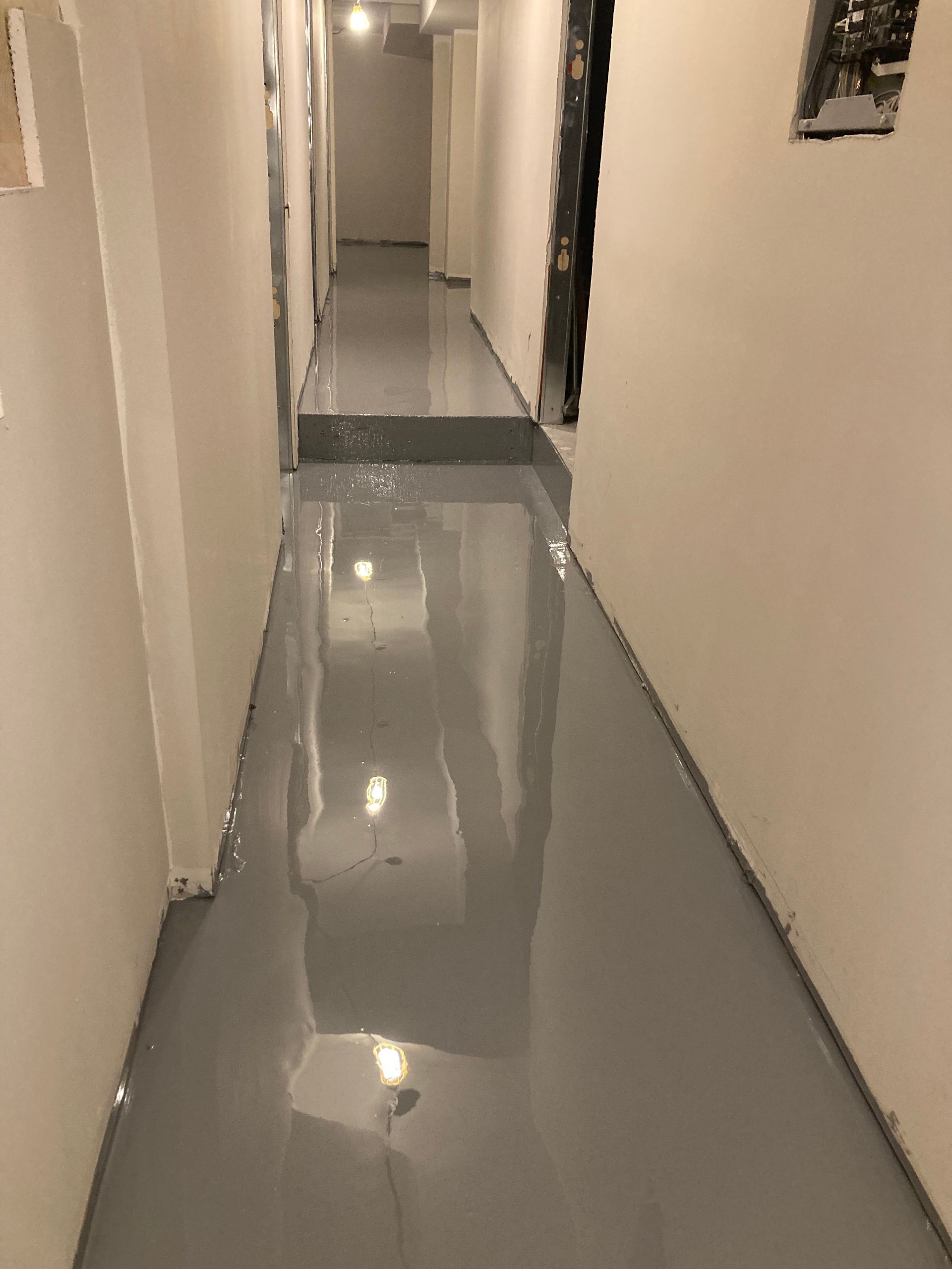 A long hallway with a gray floor and white walls.