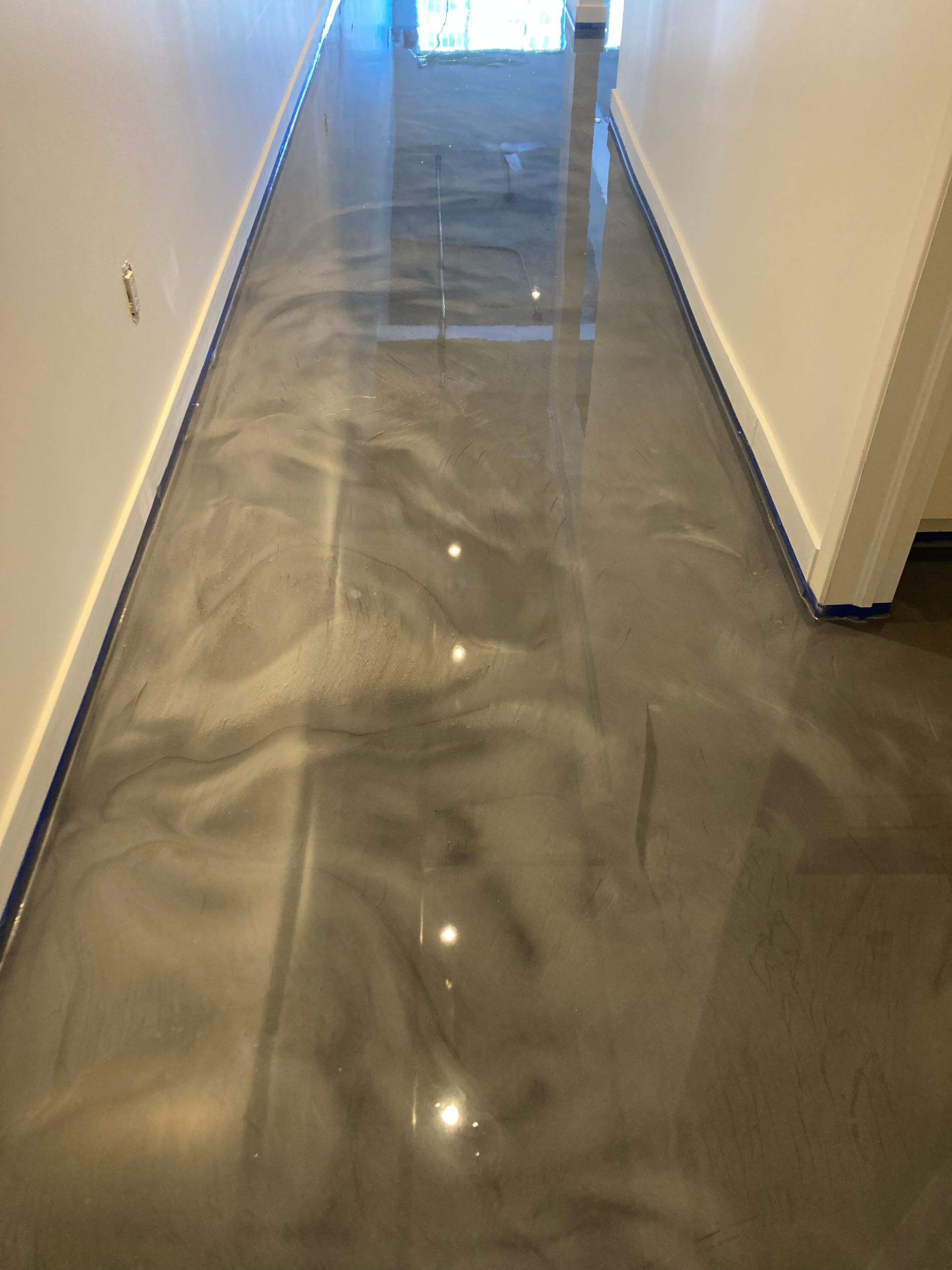 A hallway with a shiny metallic floor and white walls.