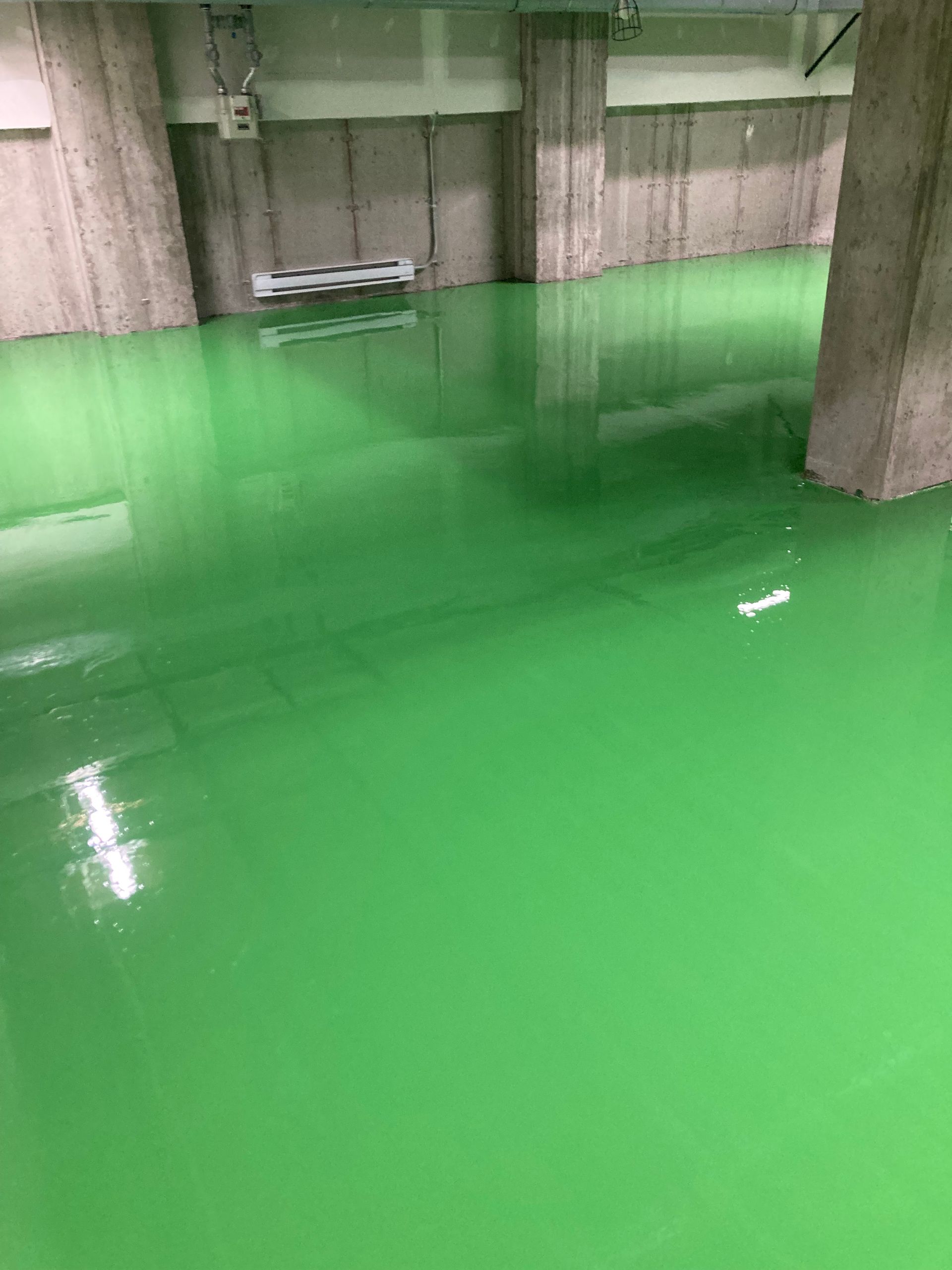 A green floor in a building with concrete walls.