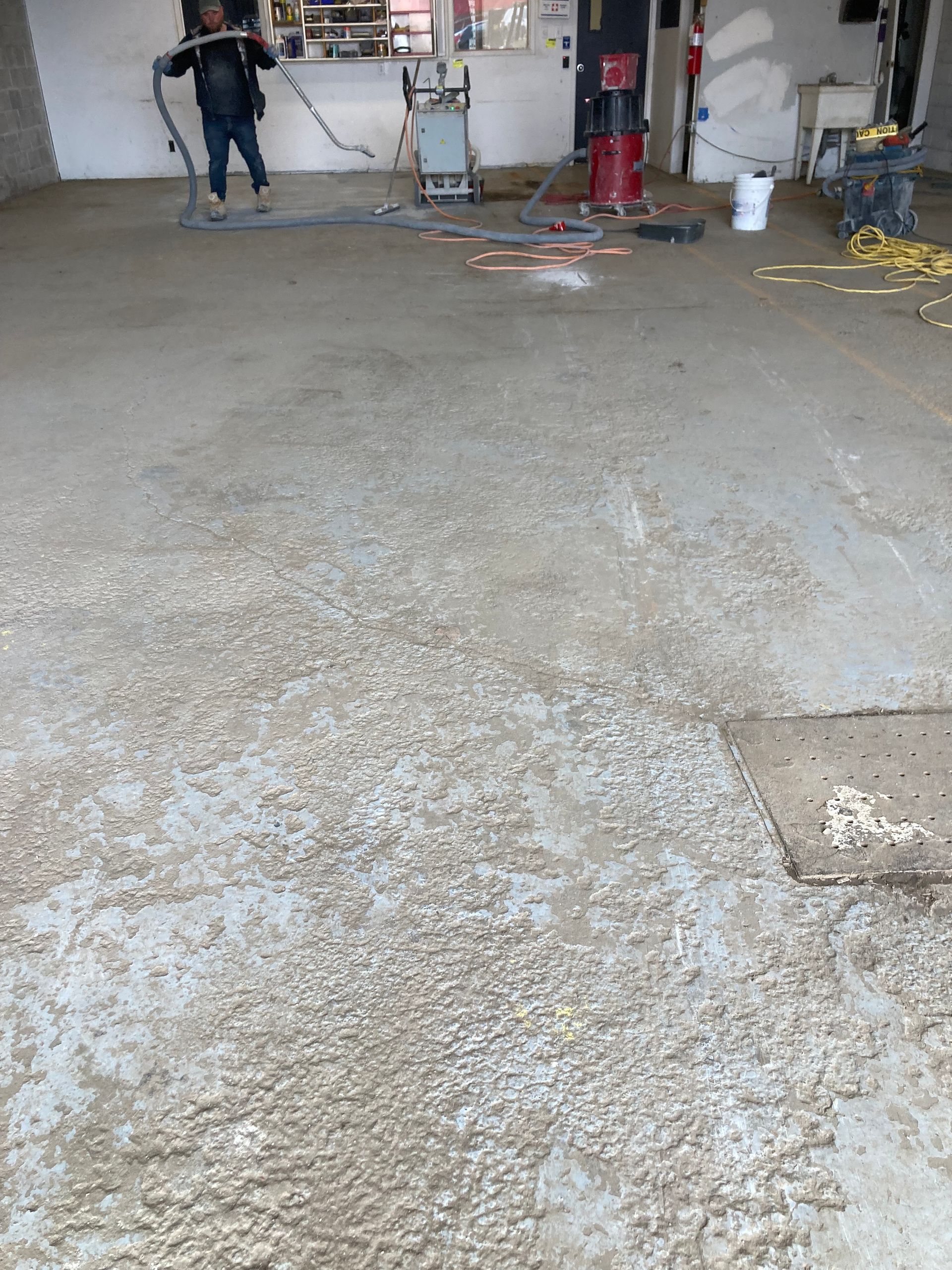 A man is standing in a garage with a vacuum cleaner