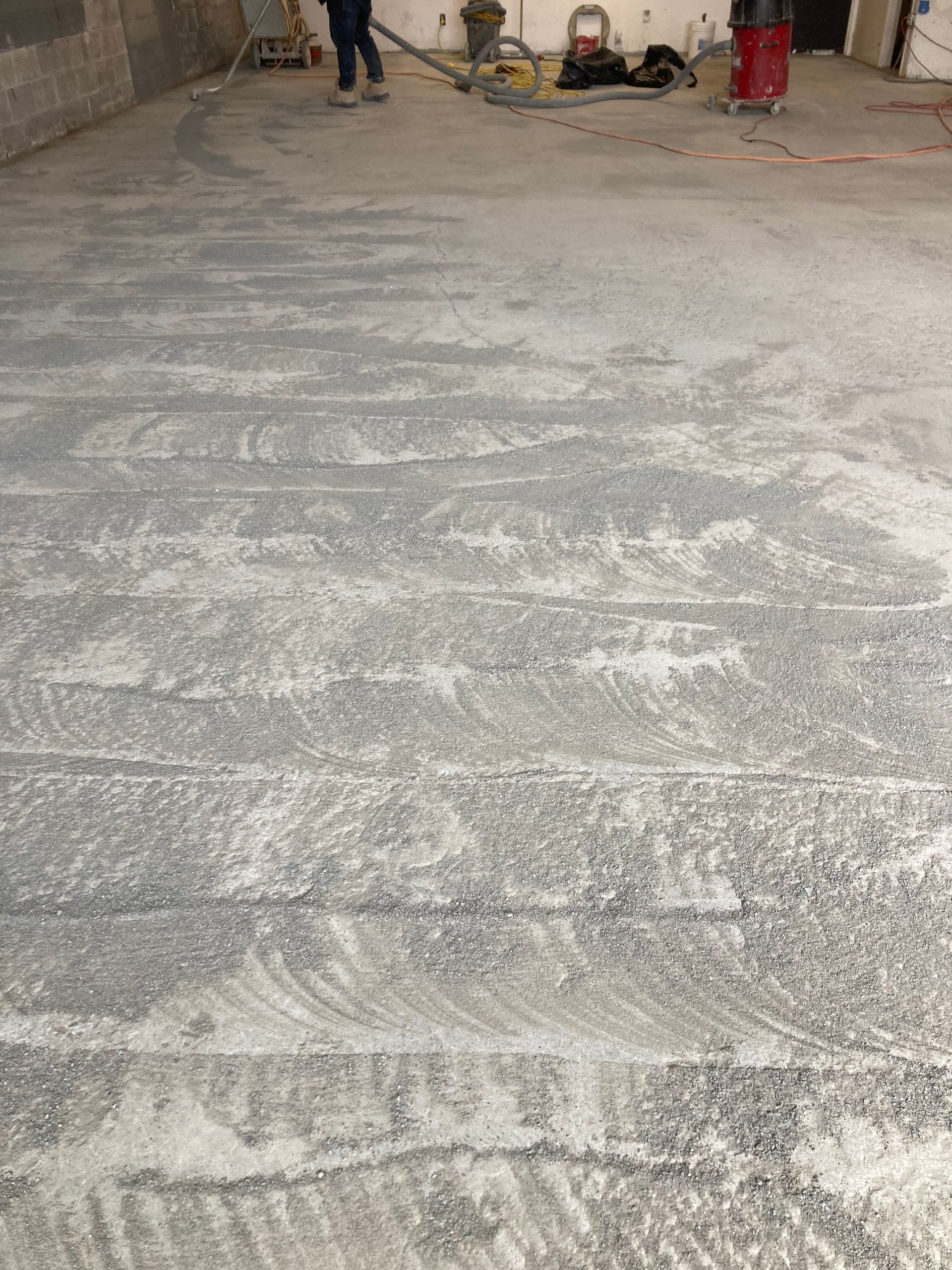 A person is cleaning a concrete floor with a vacuum cleaner.