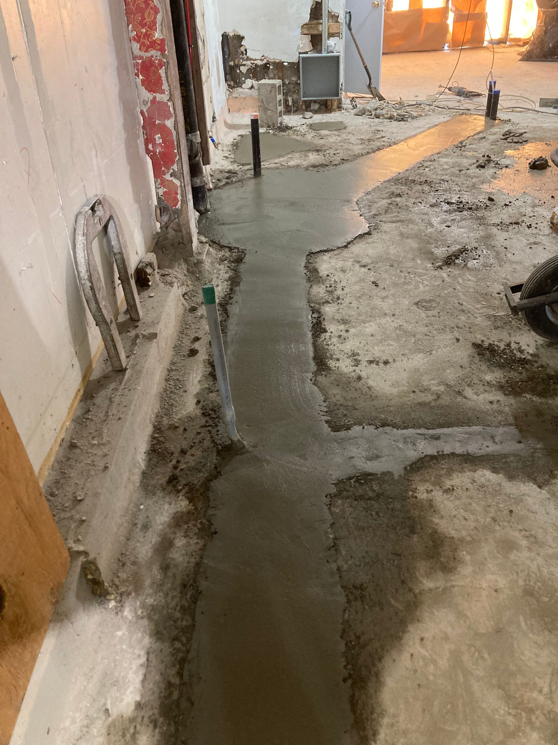 A concrete walkway is being built in a basement.