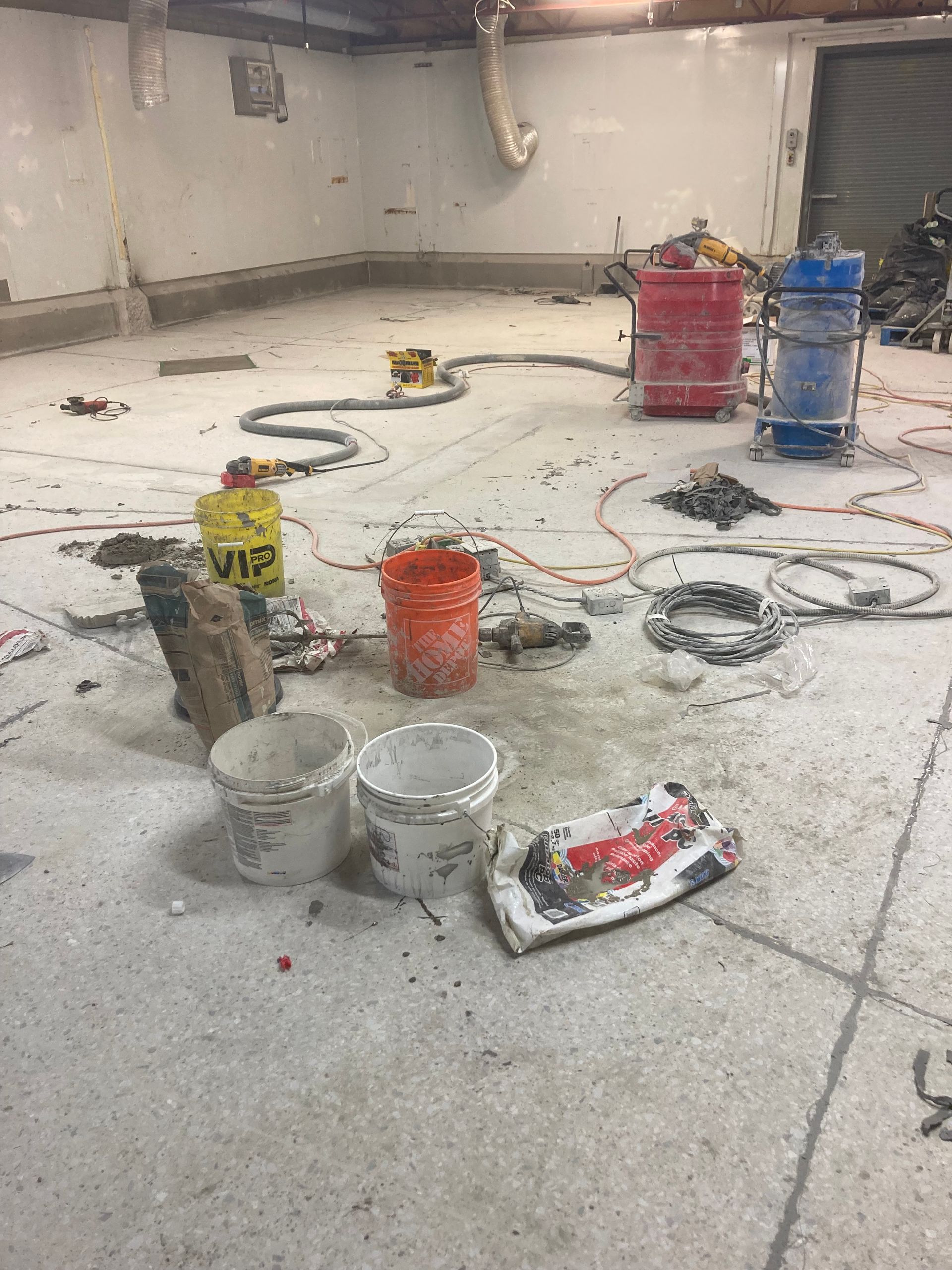 A messy room with buckets of paint and tools on the floor.