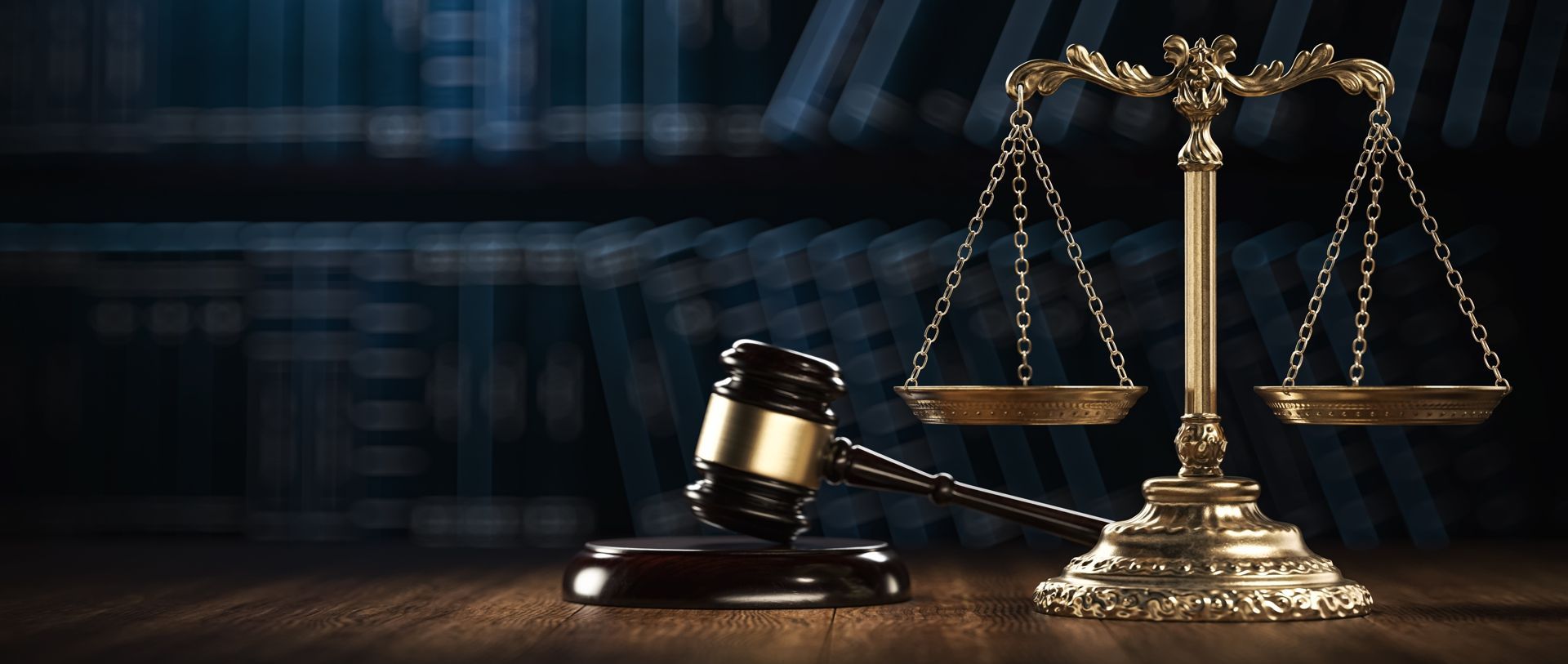 Gavel and golden scales of justice on a wooden surface, dark background.