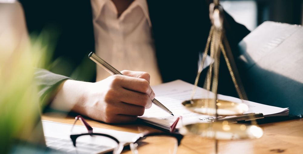 Lawyer taking notes, with a scale of justice on the table.