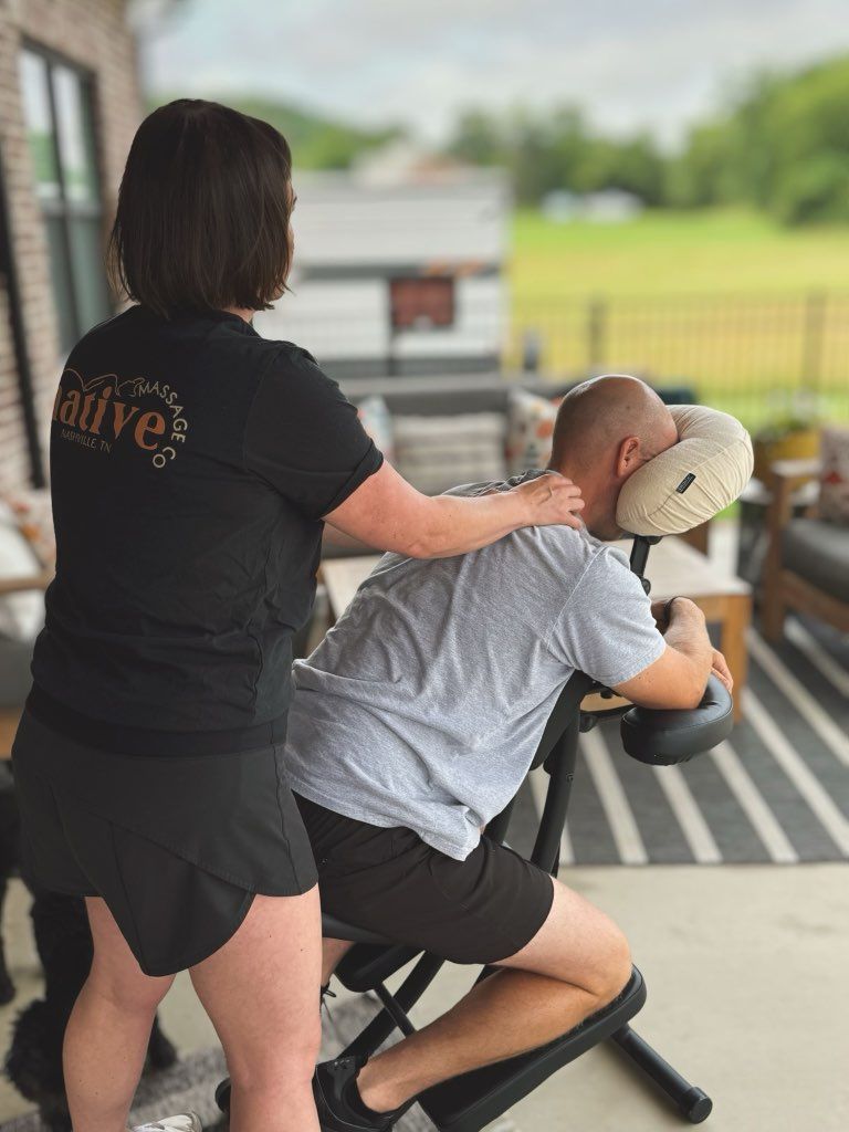 Woman giving a massage to a man in a massage chair outdoors.