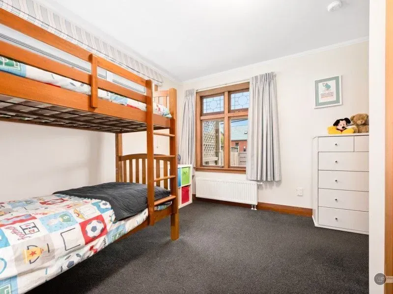 Bright children's bedroom with bunk bed, dresser, window, and gray carpet