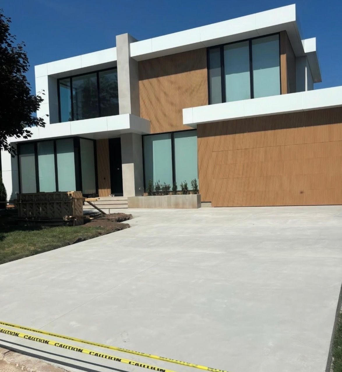Modern two-story house with wood siding, large windows, and a wide concrete driveway