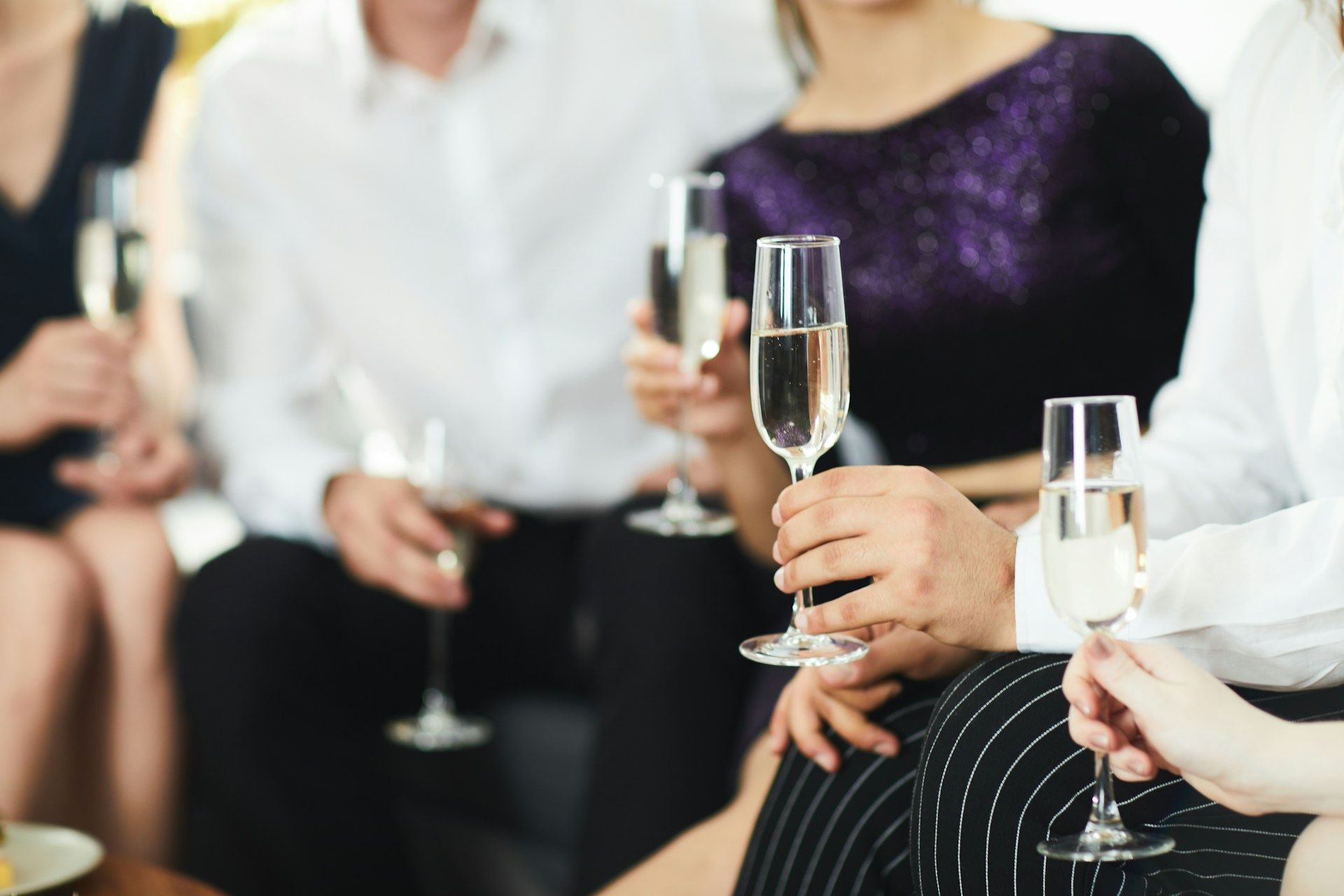 People in formal attire holding champagne flutes, indoors.
