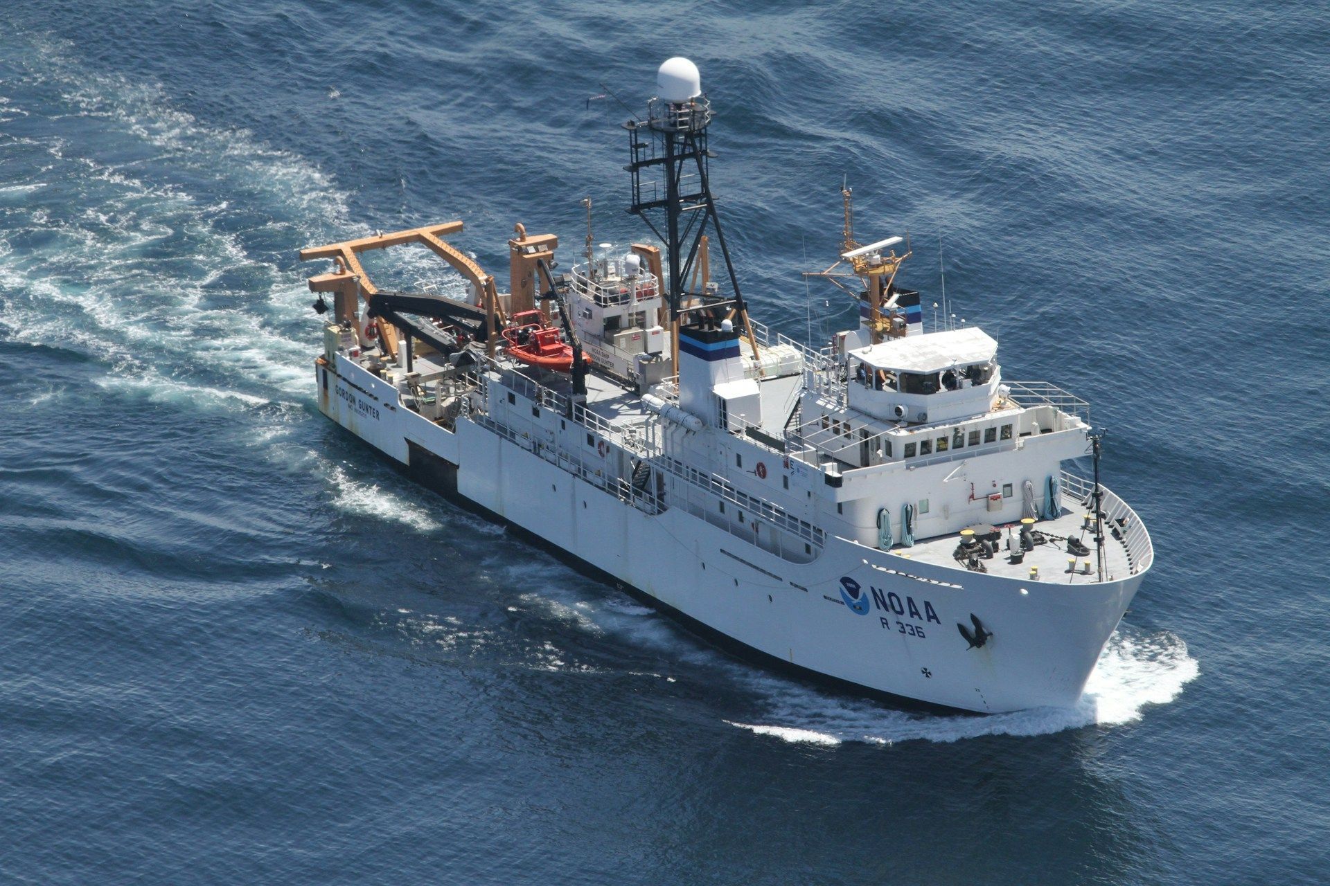 White research vessel sailing on blue ocean.