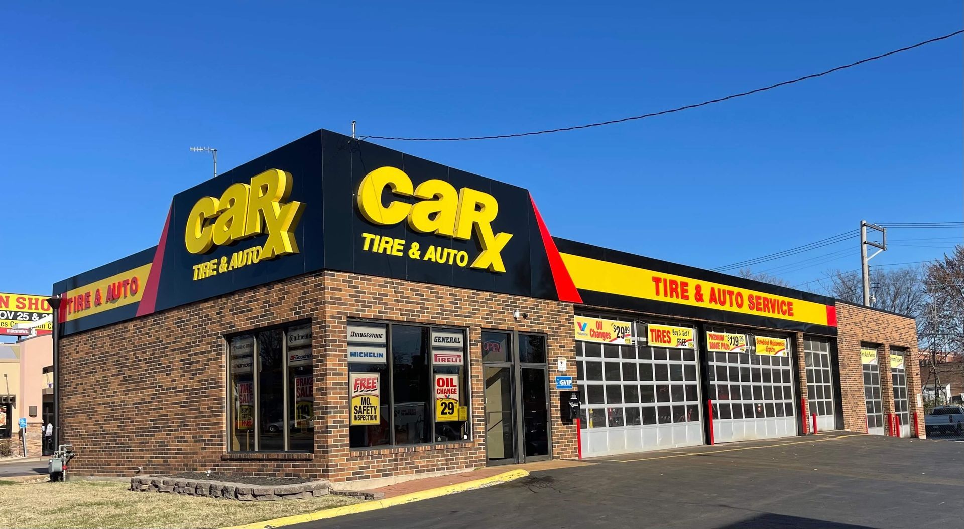 CarX Tire & Auto shop with a brick facade, black and yellow signage, and garage doors.