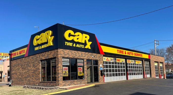 CarX Tire & Auto shop with a brick facade, black and yellow signage, and garage doors.