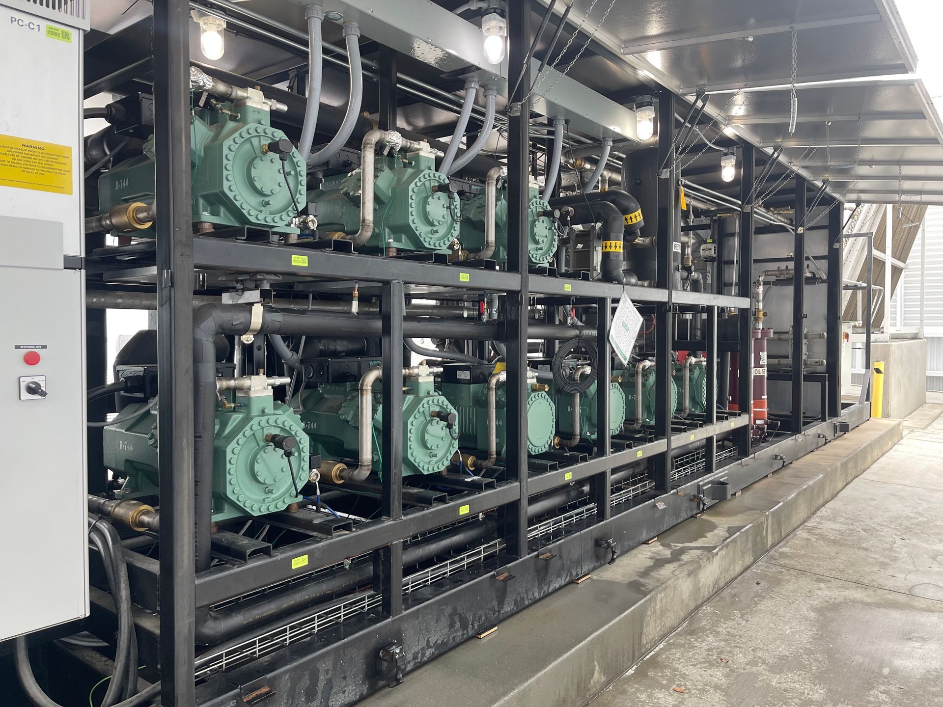A row of compressors are sitting on a shelf in a building.