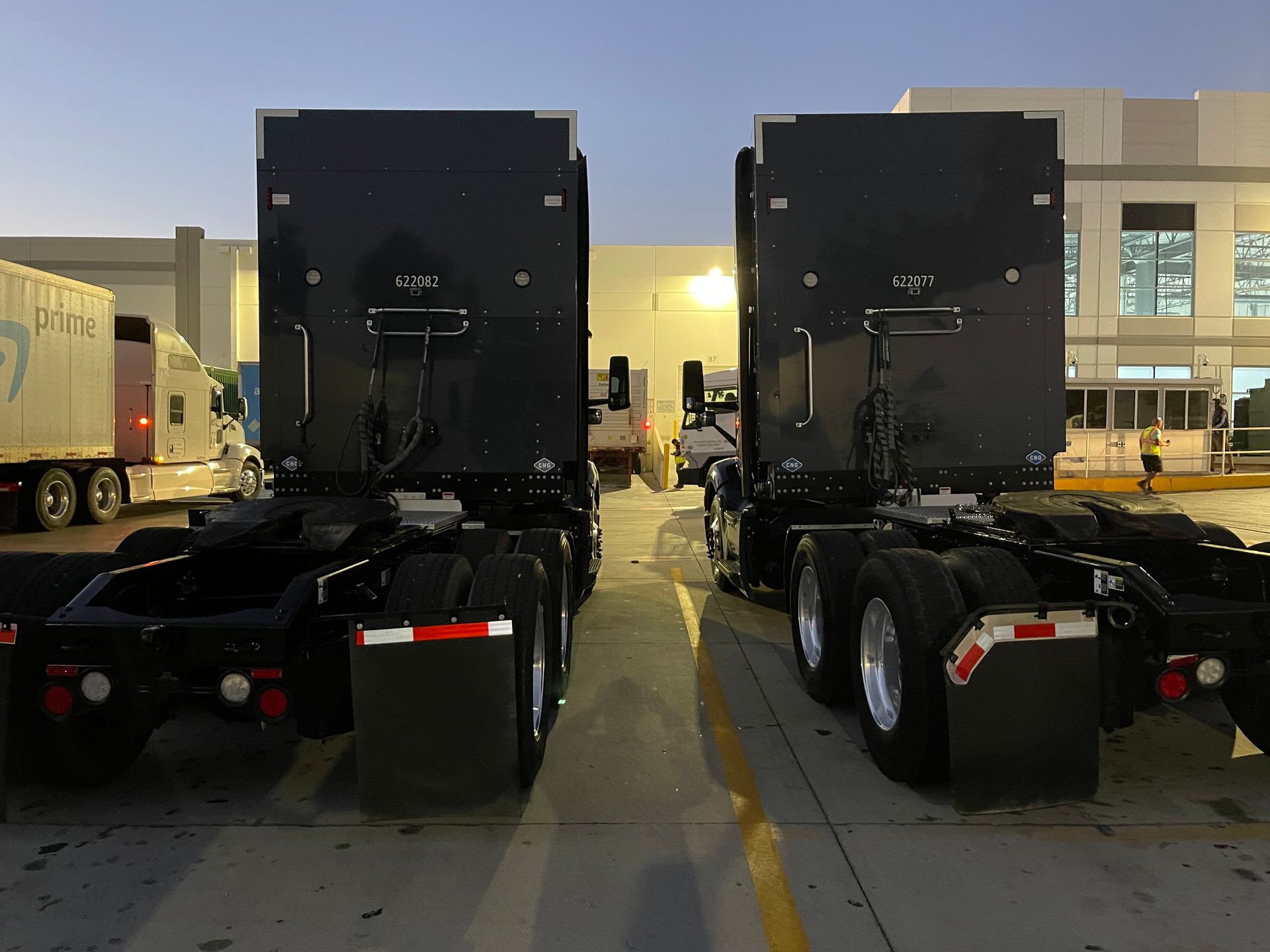 Two semi trucks are parked next to each other in a parking lot.