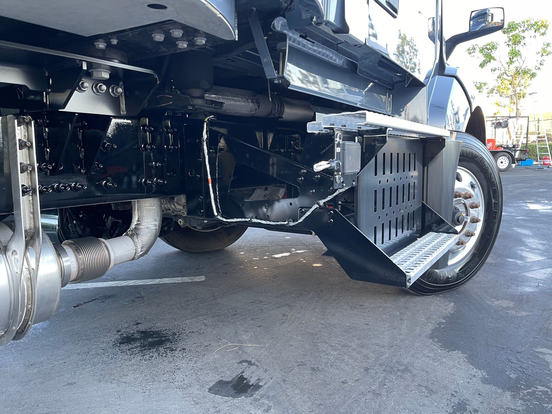 A truck is parked in a parking lot with the exhaust pipe visible.
